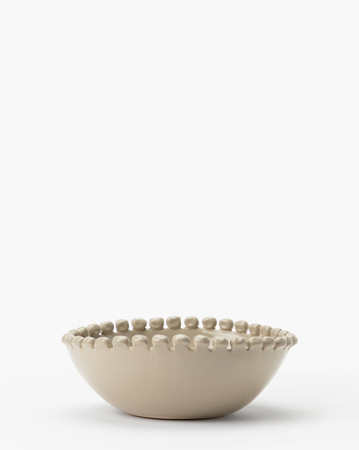 The Malibu Bowl is a beige ceramic dish with a matte finish and a rim of raised, rounded beads, creating a unique kitchen accent, by McGee & Co. Shown against a plain white background.