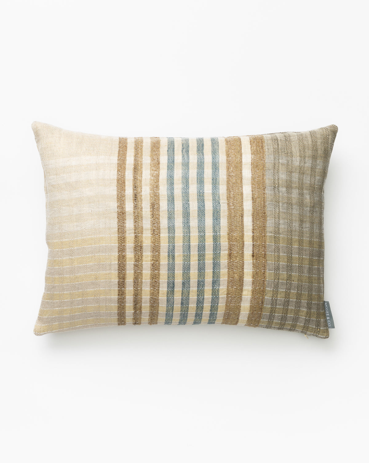 The Margaret Stripe Pillow Cover is rectangular and handwoven, featuring vertical beige, tan, gold, and light blue stripes on a white background. Made from natural materials with a small gray fabric tag on one side by McGee & Co.