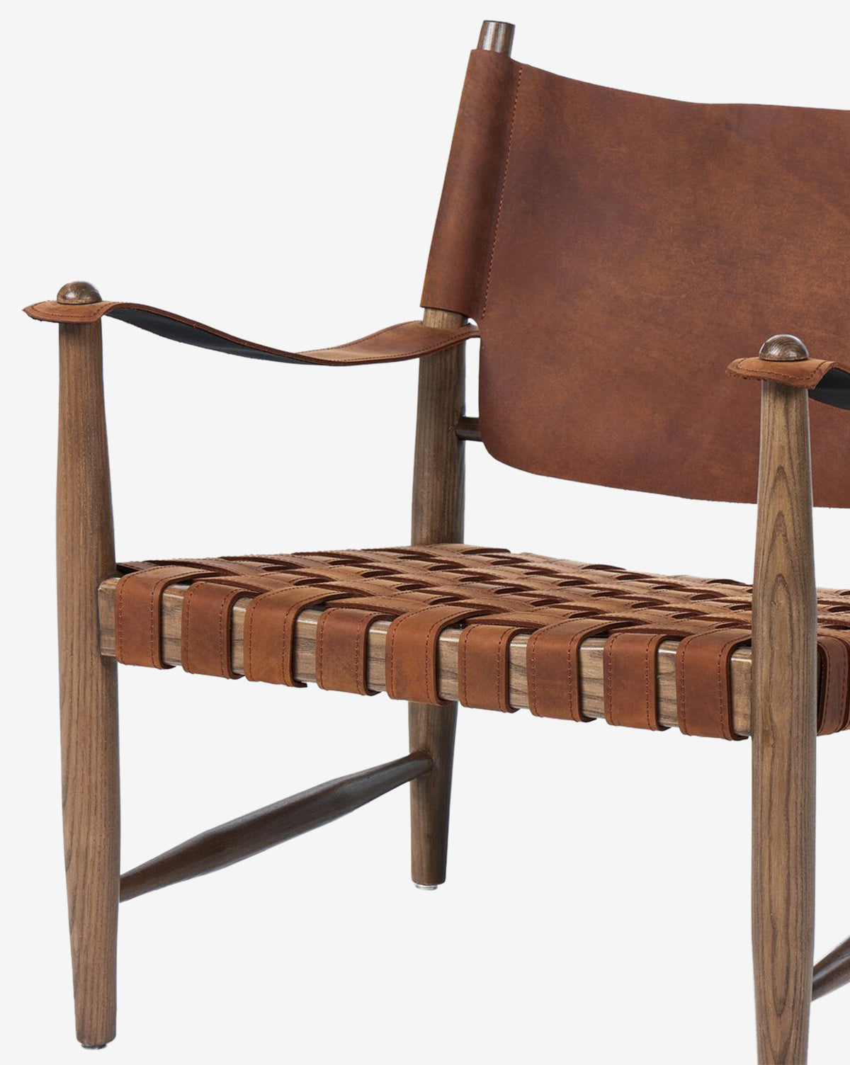A close-up of the Maris Lounge Chair showcases its wooden frame, brown top-grain leather woven seat and backrest. The chair’s vintage-inspired, minimalist design exudes stylish charm by McGee & Co.