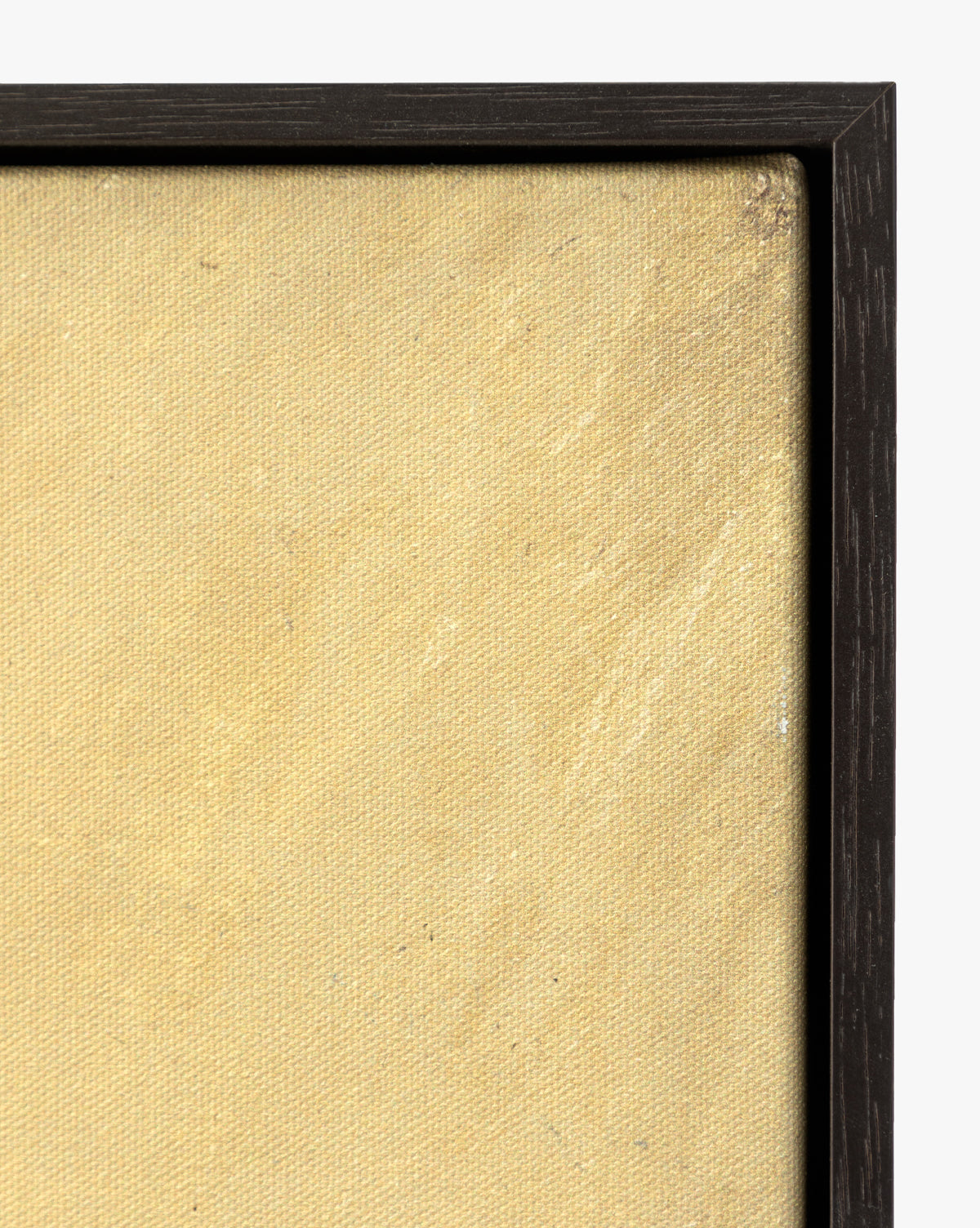A close-up of the top right corner of Mark Making, a textured, beige gallery-wrapped canvas in a slim, dark wooden frame, shown against a white background, by McGee & Co.