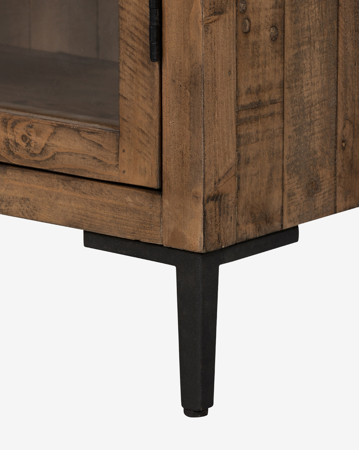 Close-up of the bottom corner of the Maverick Cabinet, made from reclaimed pine with a glass-paneled door and black iron hardware, set against a plain white background by McGee & Co.