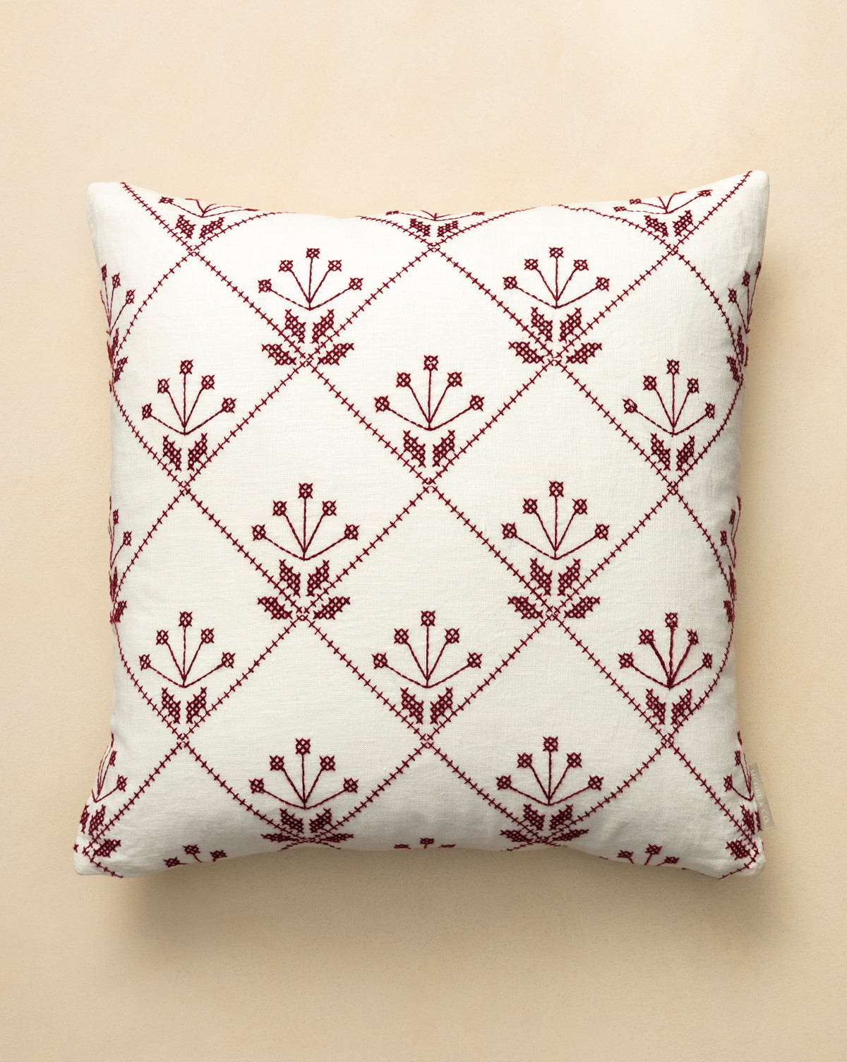 The McCallister Pillow Cover features a square cream base adorned with maroon stitched flowers in diamond grids—ideal for vintage decor lovers or adding charm to your holiday home, by McGee & Co.