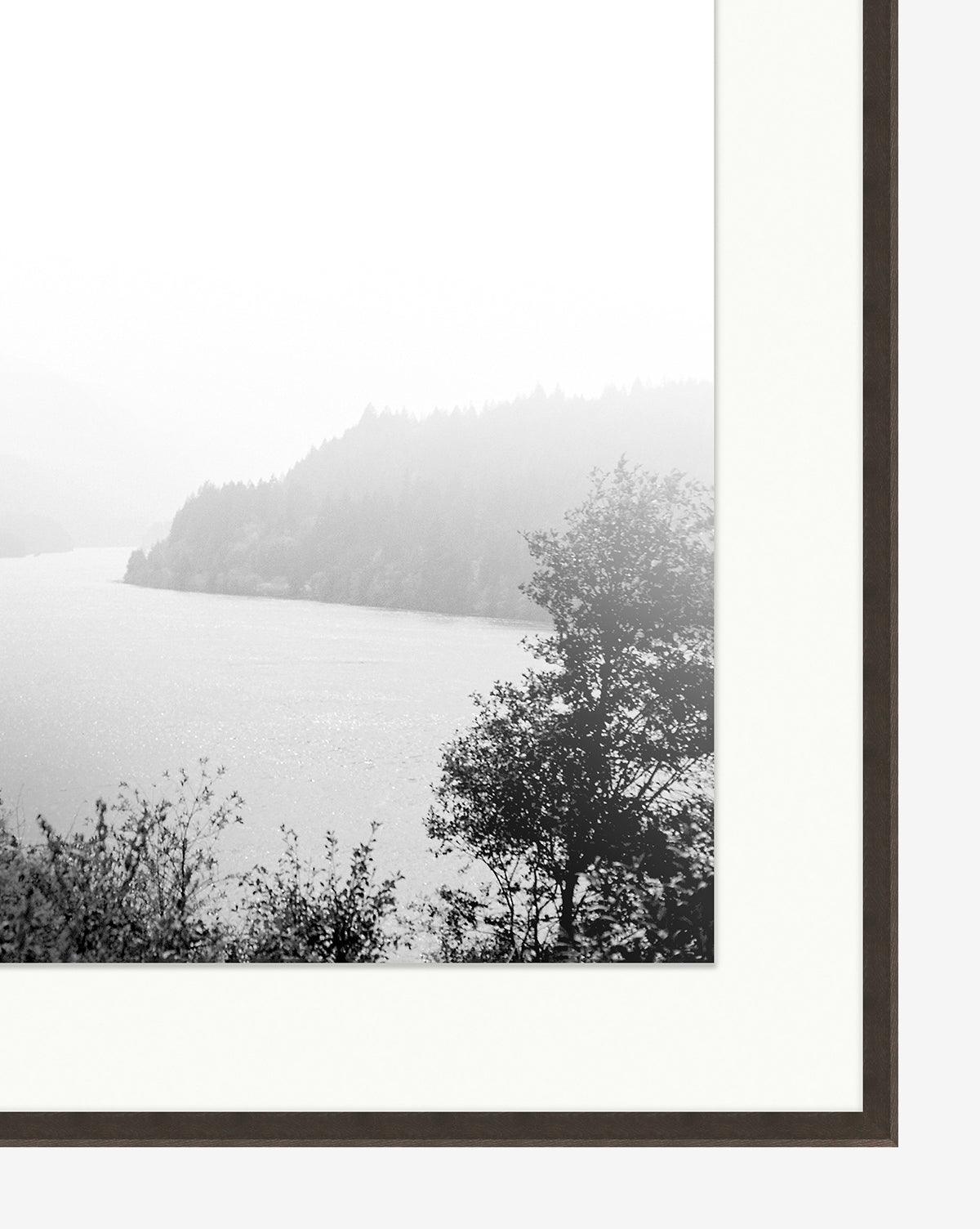 Mist on the Lake is a gallery-quality black and white giclee print depicting a calm lake with wooded hills and trees, elegantly presented in a simple dark frame with a white mat.