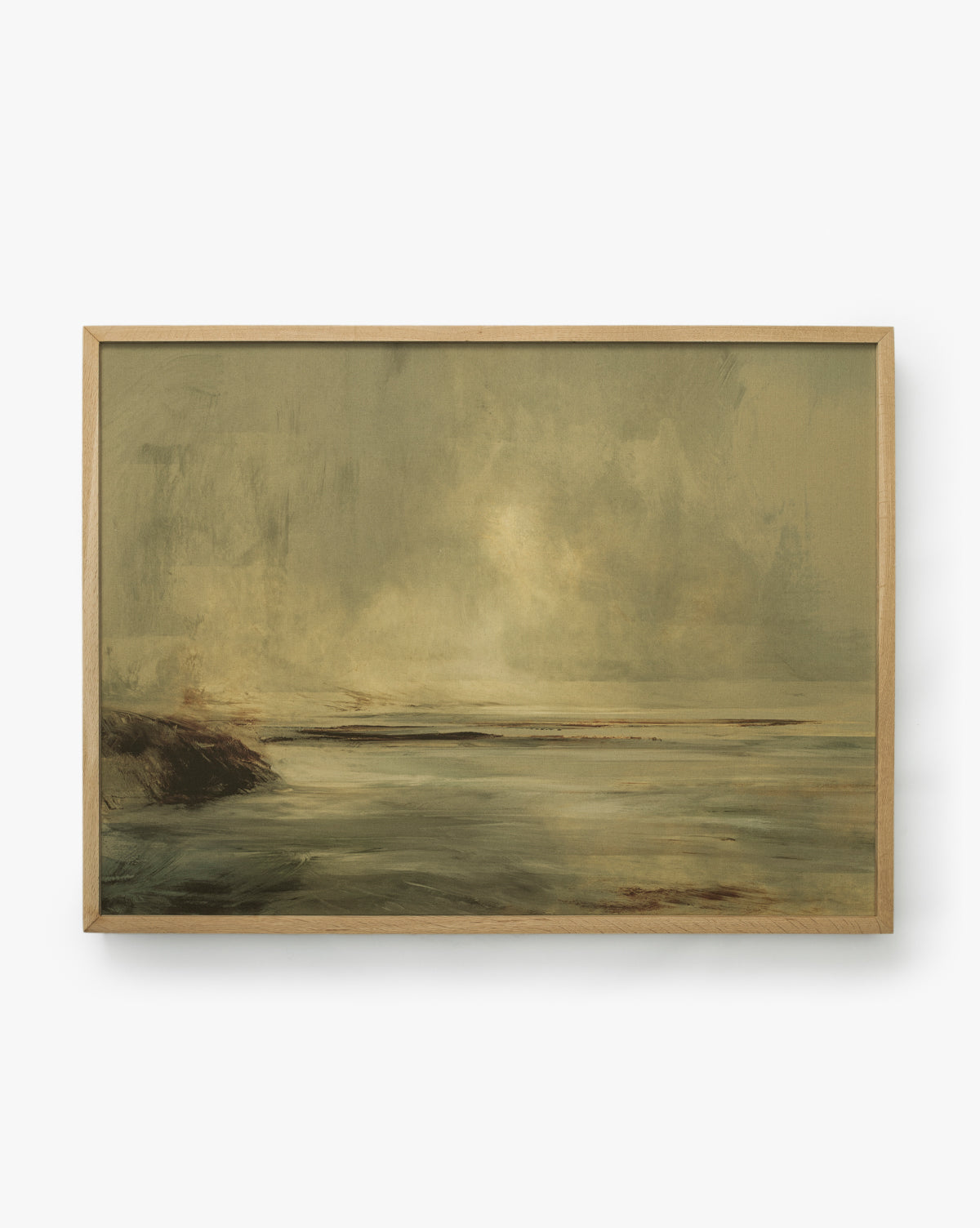 The Misty Blue Headland is a framed giclee print of a misty coastal landscape with calm water, a rocky shoreline on the left, and an atmospheric sky in soft earthy tones, presented in an elegant white oak frame, by McGee & Co.