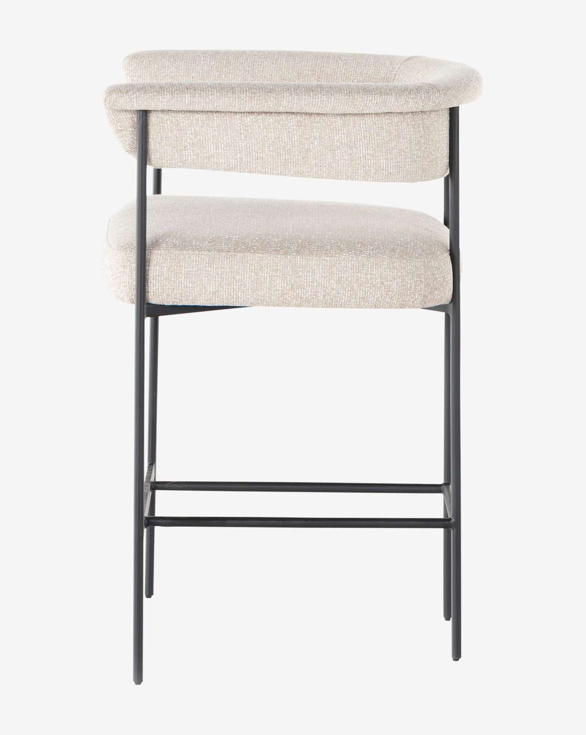 The Monson Stool is a modern bar stool with a light beige upholstered seat and backrest, slim black metal legs, and a minimalist design, displayed against a white background by McGee & Co.