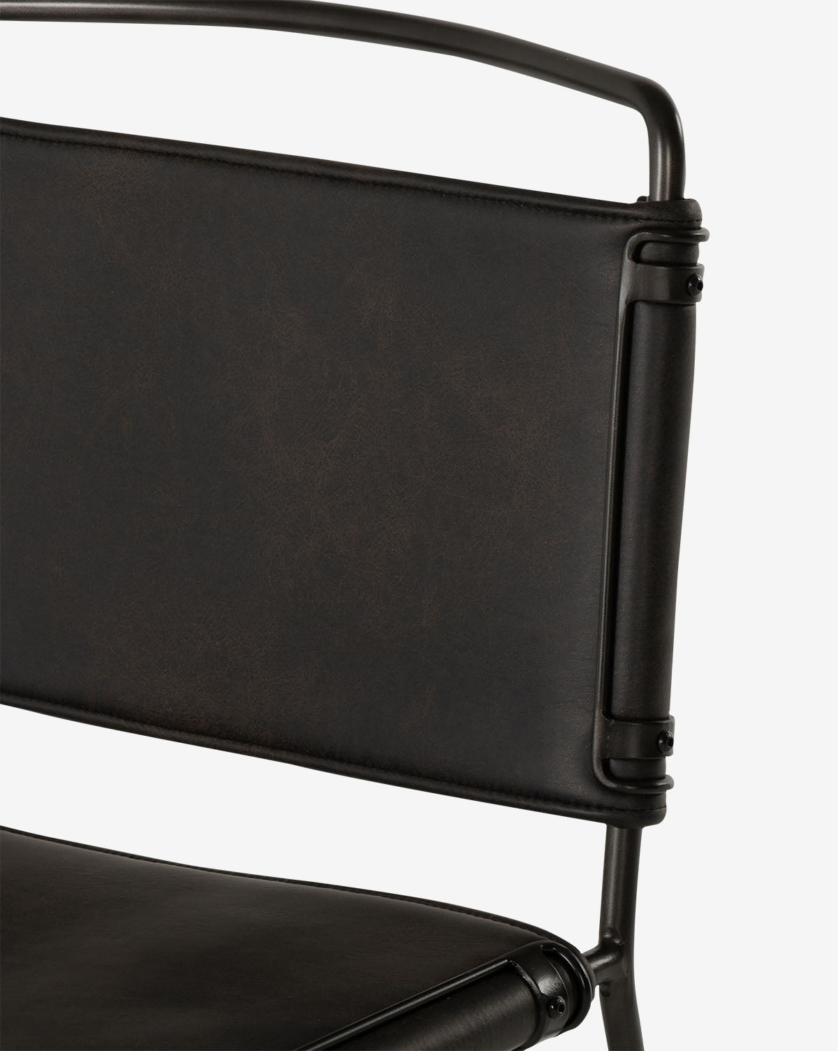 Close-up of the Moore Dining Chair, featuring a dark brown leather or faux leather backrest and seat, black metal frame, contoured canvas seating, and visible bolts for an industrial look by McGee & Co.
