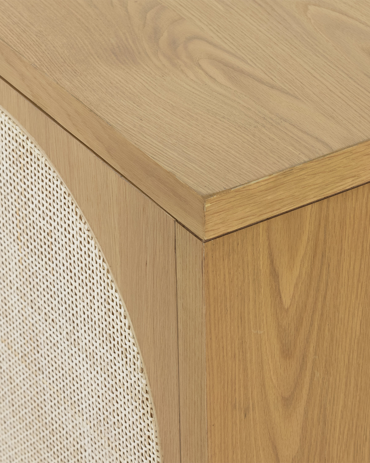 Close-up of the Mora Sideboards corner, crafted in honey oak and featuring a rounded rectangular beige woven fabric panel with caning detail, by McGee & Co.