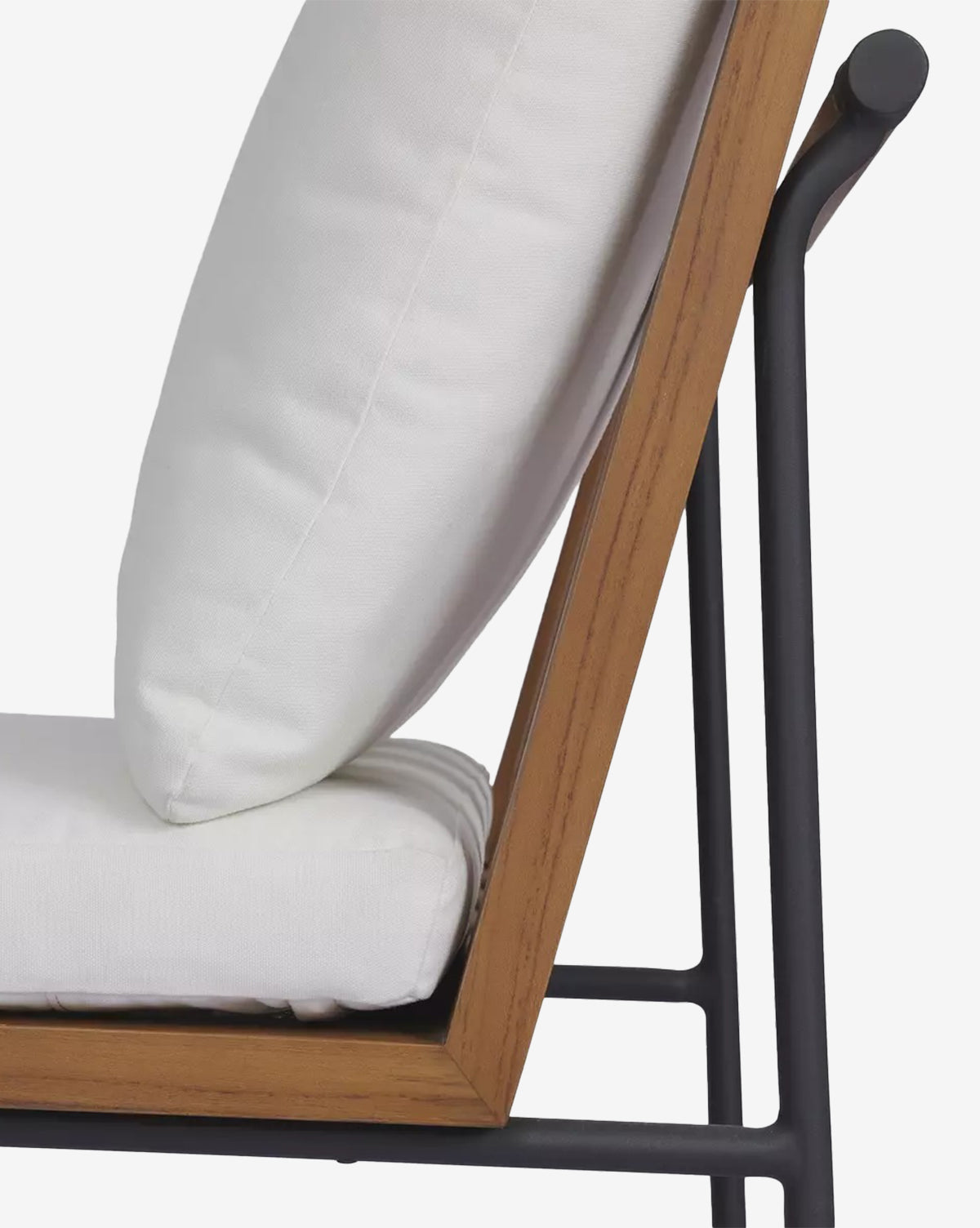 Side view of the Neal Outdoor Dining Chair, featuring a black metal frame, solid teak accents with angled wooden armrests, and thick white performance fabric cushions on the seat and back, by McGee & Co.