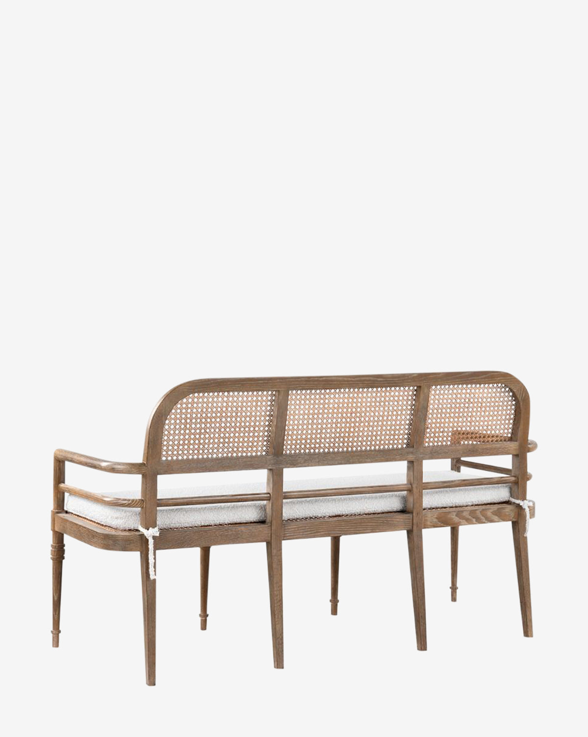 The Nestor Bench showcases an oak frame, cane backrest, three boucle fabric cushions, and four light brown legs. Its elegant, minimalist design stands out against a plain white background by McGee & Co.