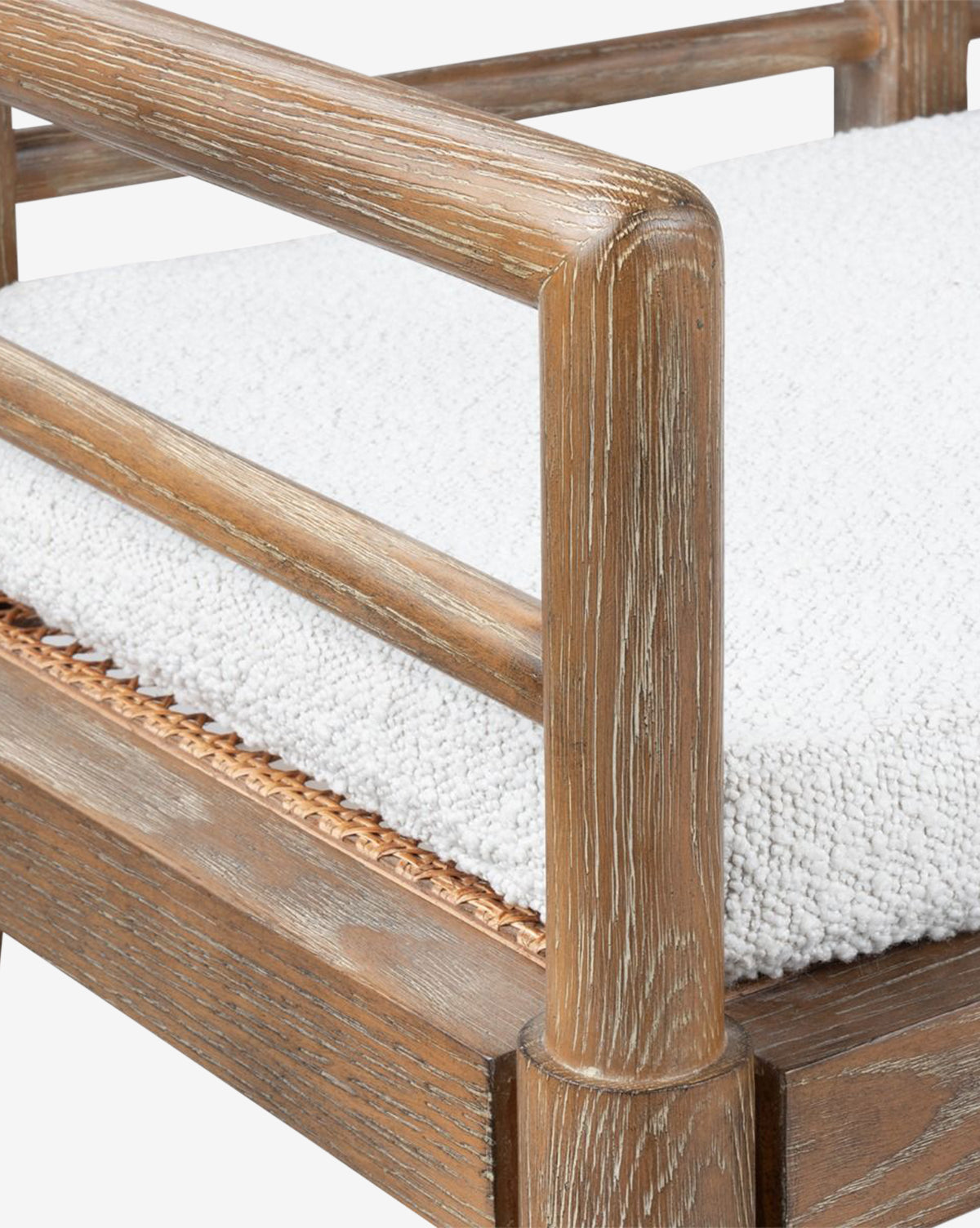 Close-up of the Nestor Bench armrest with a light brown oak frame, highlighting wood grain detail. Features a textured white boucle cushion and woven accents beneath the seat, by McGee & Co.