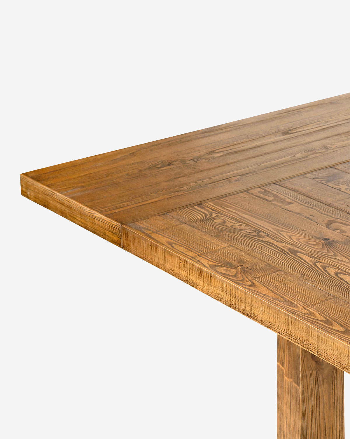 Close-up of the corner of the Niran Extension Dining Table, made from solid pine wood with a natural grain finish, highlighting its texture and detail against a plain white background, by McGee & Co.
