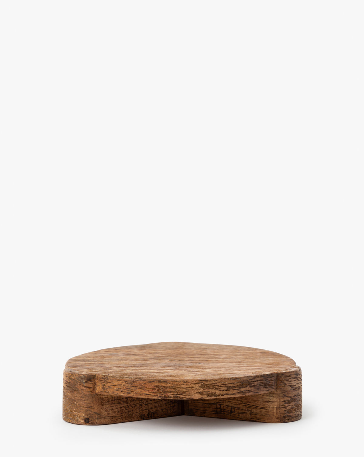 The Norfolk Wood Pedestal is a small, heart-shaped stand made from mango wood with a natural grain, ideal for displaying plants, by McGee & Co. Shown here against a plain white background.