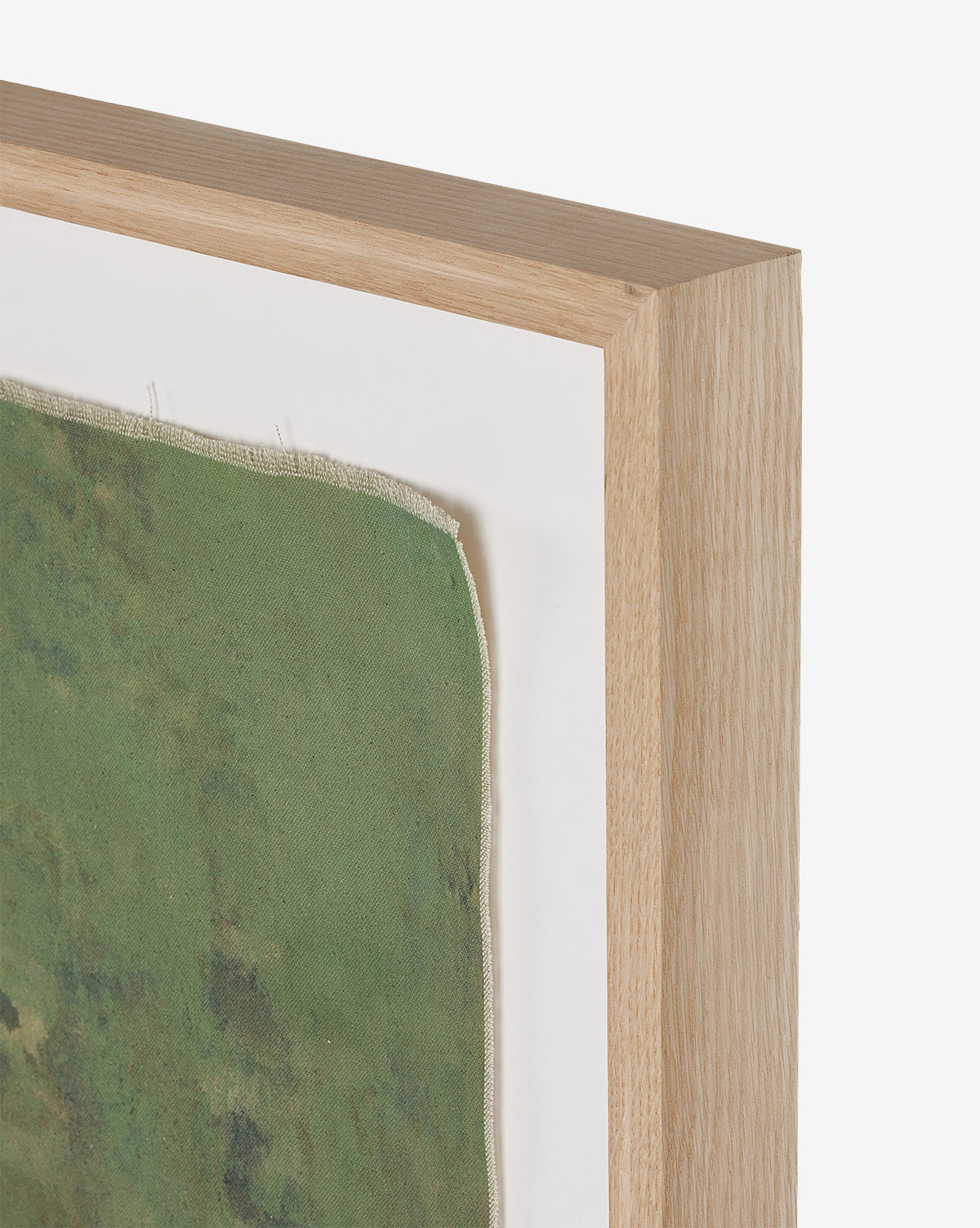 Close-up of a wooden frame showcasing Carrying the Olive Branch No. 2 by Tyler Guinn—green fabric with frayed edges brings organic, raw canvas style to a crisp white background.