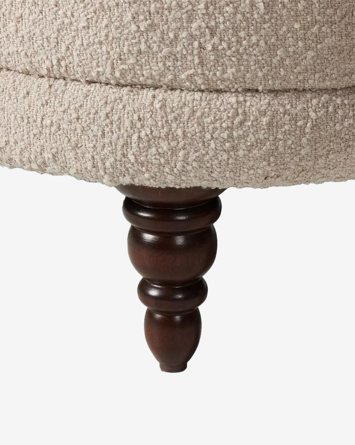 Close-up of the Olivette Slipper Chair’s dark wood turned leg, with beige textured upholstery in a nubby, boucle style. This chair blends traditional and modern design, shown against a plain white background, by McGee & Co.