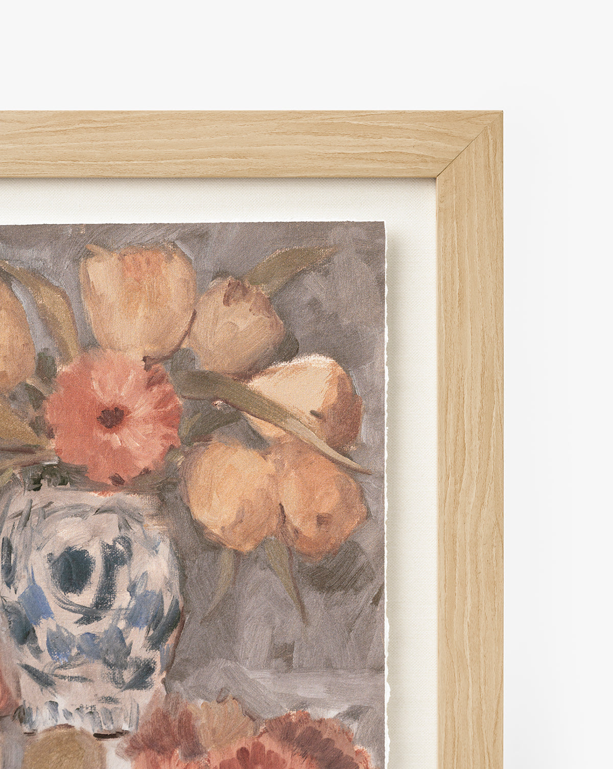 A close-up of Orange Florals Still Life, a framed watercolor with peach-toned flowers in a blue and white vase. Set in a light wood frame with a gray background, this elegant art suits any space by McGee & Co.