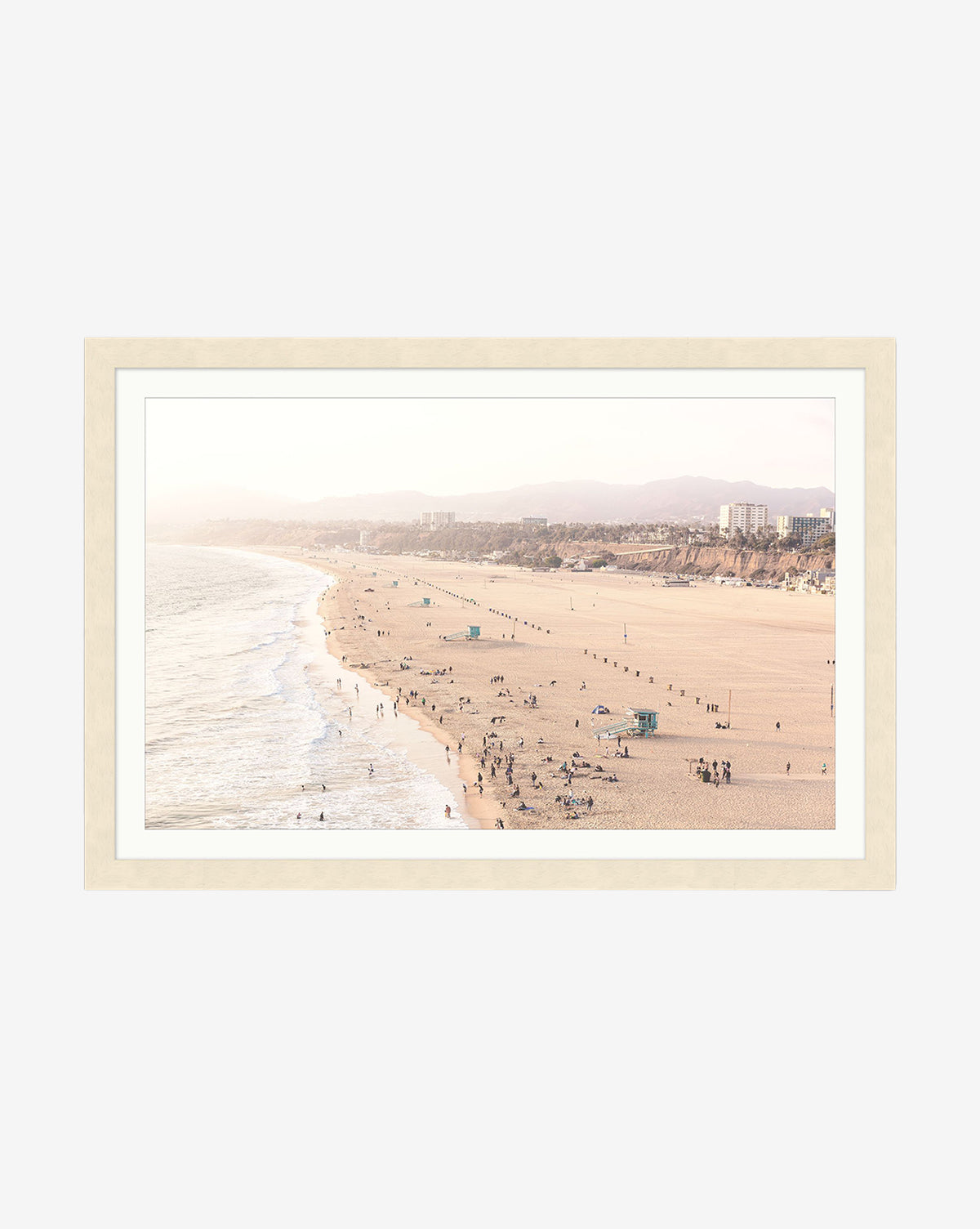 Framed giclee print Pacific Perspective—a wide sandy beach with scattered people, gentle waves, and distant buildings under a hazy sky in a natural wood frame, by McGee & Co.
