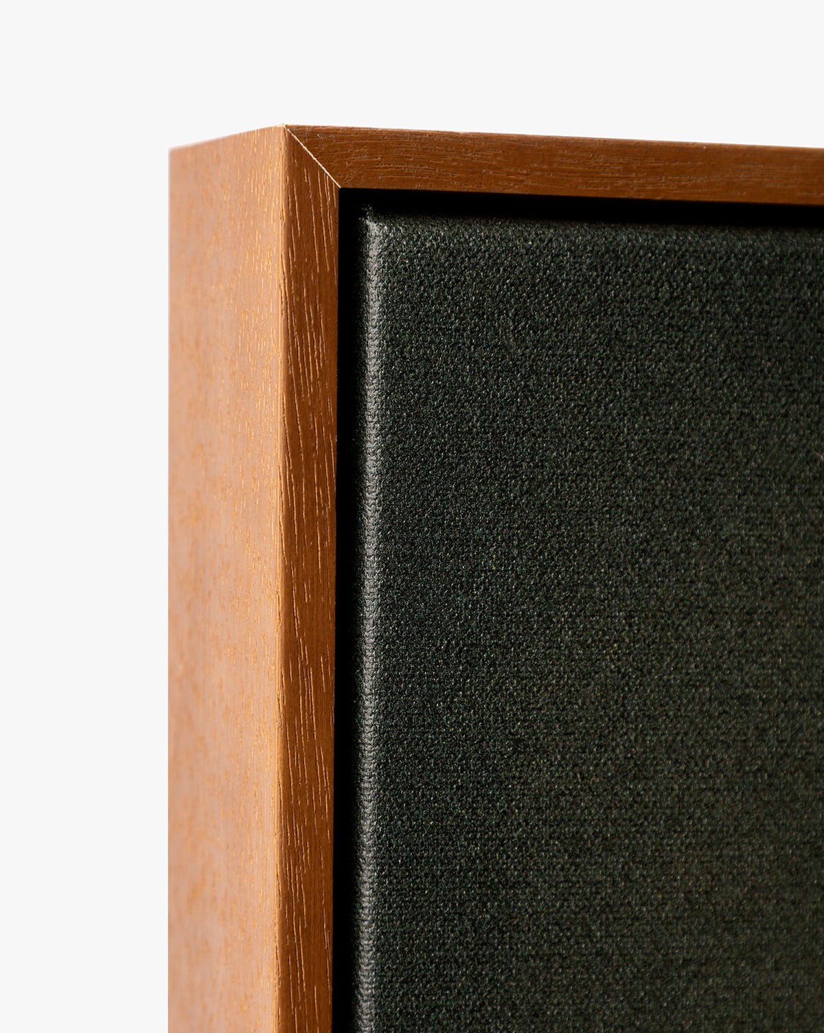 Close-up of the corner of a Painters Depths wooden-framed black fabric speaker against a white background, highlighting the wood and fabric texture, reminiscent of gallery-wrapped abstract wall art, by McGee & Co.