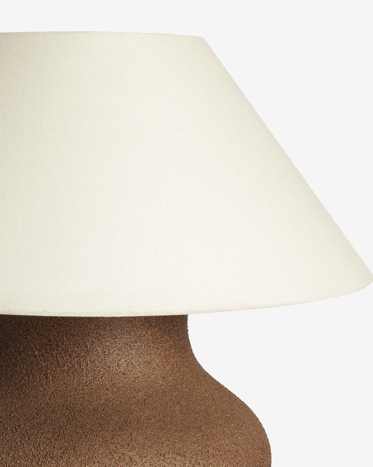 Close-up of the Parma Table Lamp, featuring a textured ceramic base and a wide ivory linen shade, set against a white background, by McGee & Co.