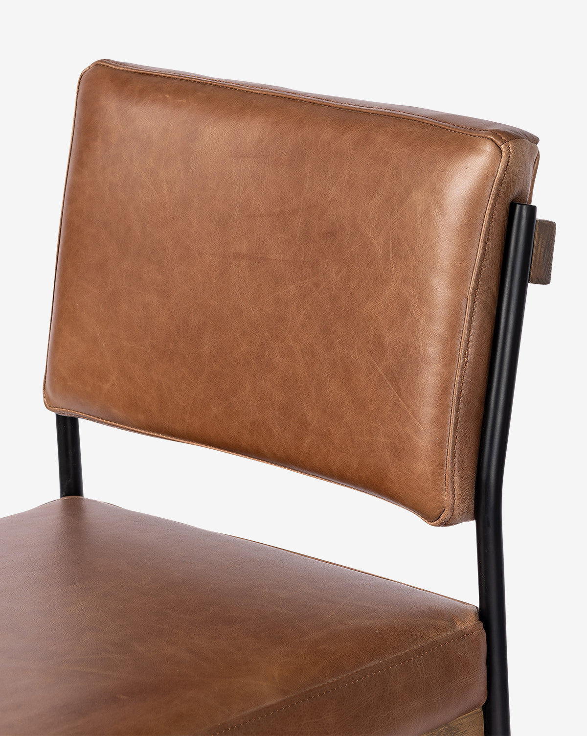 The Pascal Stool is shown in close-up, highlighting its brown leather backrest and seat with a black iron frame, set against a plain white background by McGee & Co.