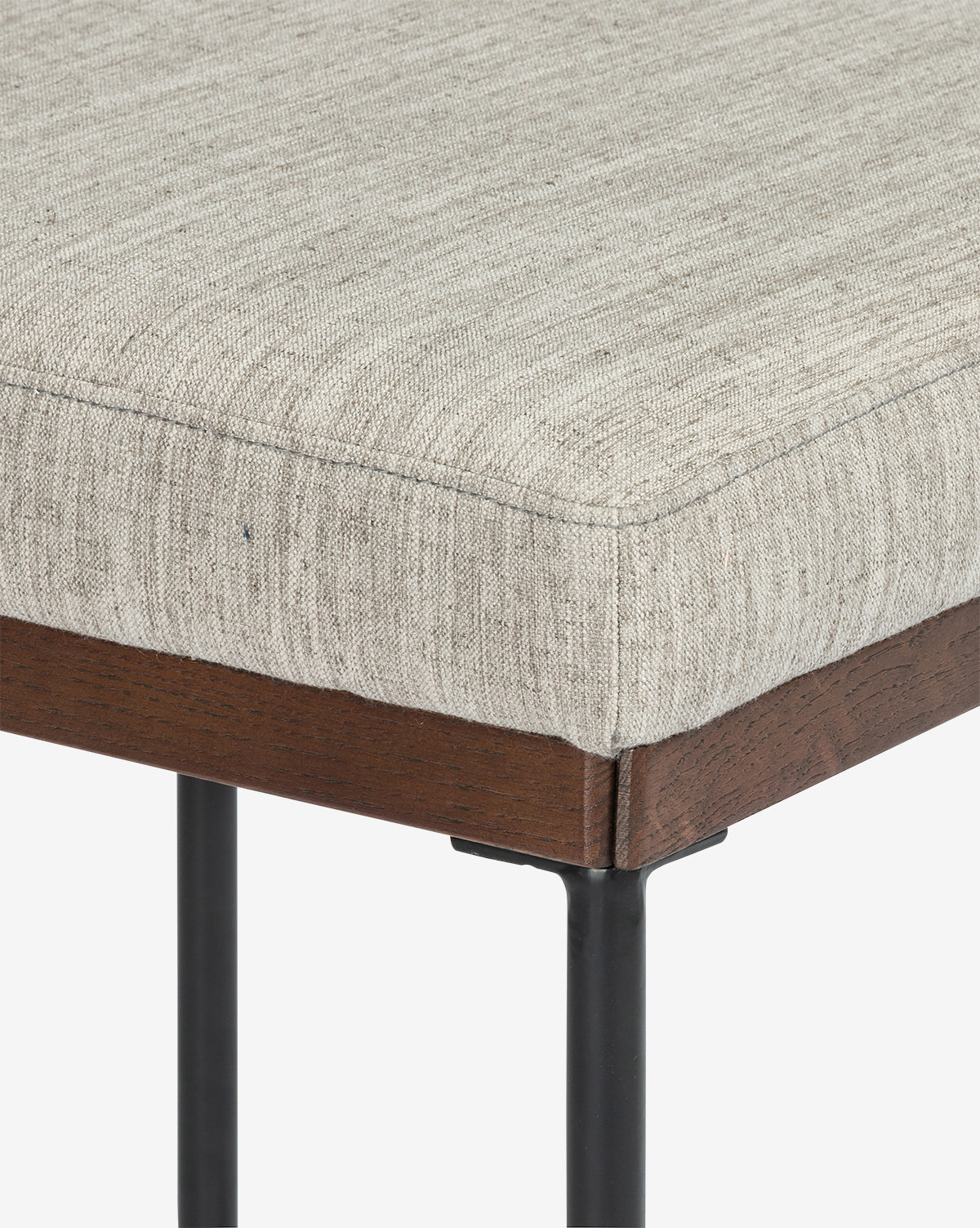 Close-up of the Pascal Stool highlights its light beige upholstered cushion, black iron frame, and metal legs against a white background, emphasizing its stylish and versatile design for any space, by McGee & Co.
