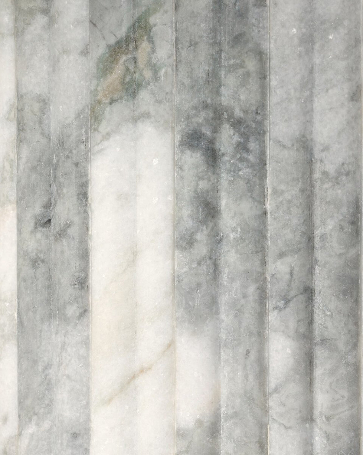 A close-up of the Patrick Dining Table reveals light gray marble with vertical grooves and subtle white and dark gray veining, highlighting its textured, contemporary surface by McGee & Co.