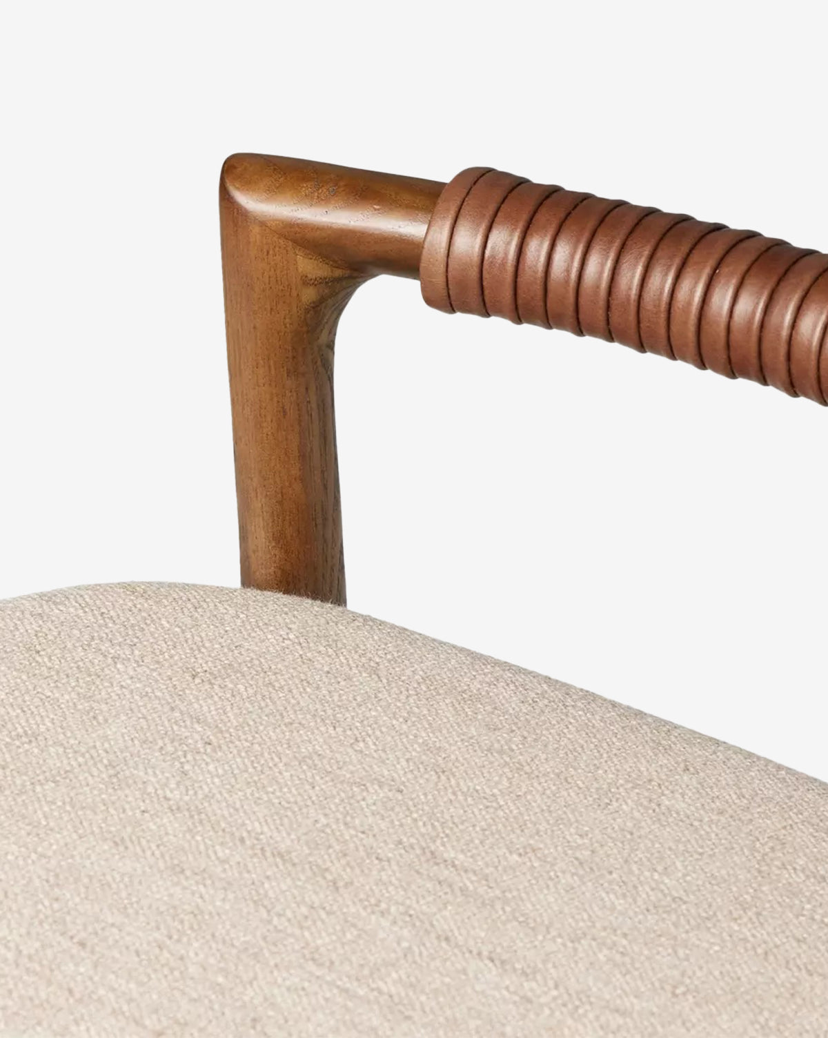 Close-up of a Four Hands Patrin Stool’s ash wood armrest, partially wrapped in coiled brown leather, beside a light beige performance-upholstered seat cushion. McGee & Co.