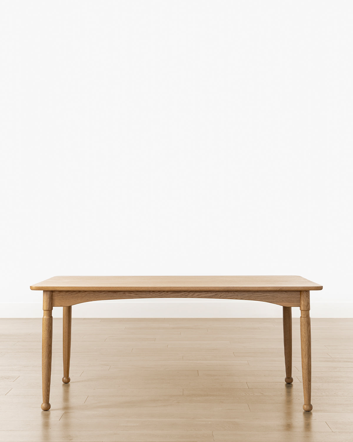 The Phipps Dining Table, featuring four legs, stands on a light wood floor against a plain white background, seamlessly blending timeless simplicity with modern traditional design, by McGee & Co.