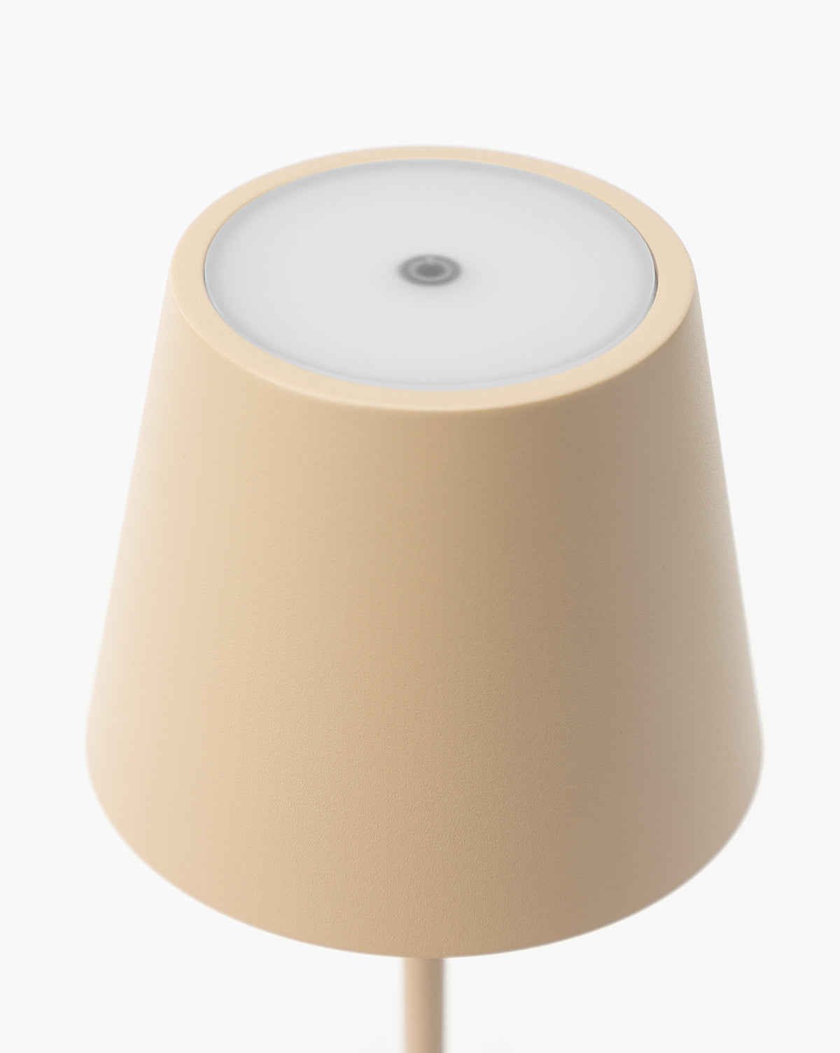 The Poldina Indoor/Outdoor Table Lamp features a minimalist beige design with a conical shade and round frosted top, viewed from above on a white background. Its smooth texture and central detail highlight modern style, by McGee & Co.
