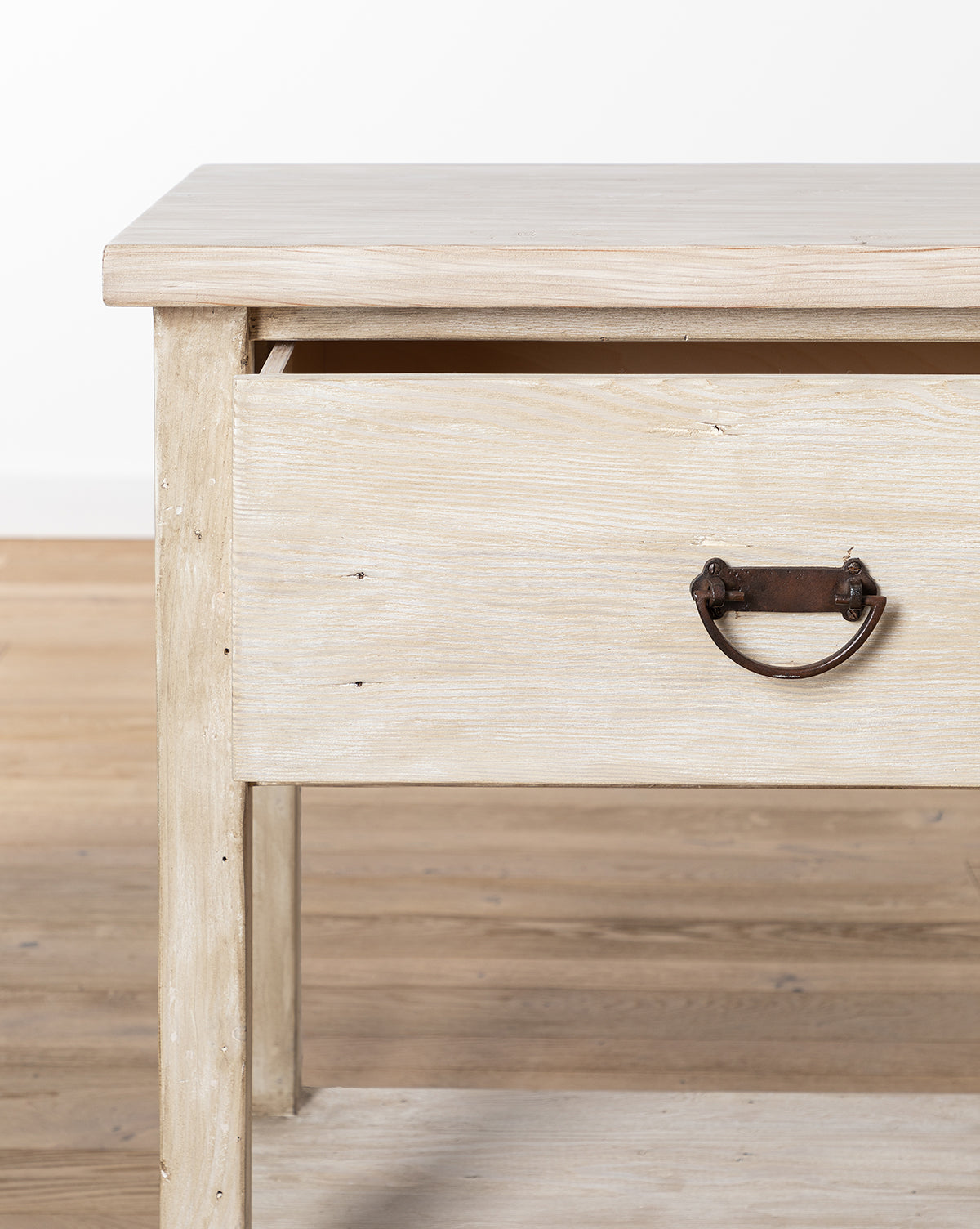 A close-up of the Martha Sideboard, crafted from reclaimed Douglas Fir in light wood, featuring a single drawer with a metal pull handle, shown on a wooden floor against a white background, by McGee & Co.