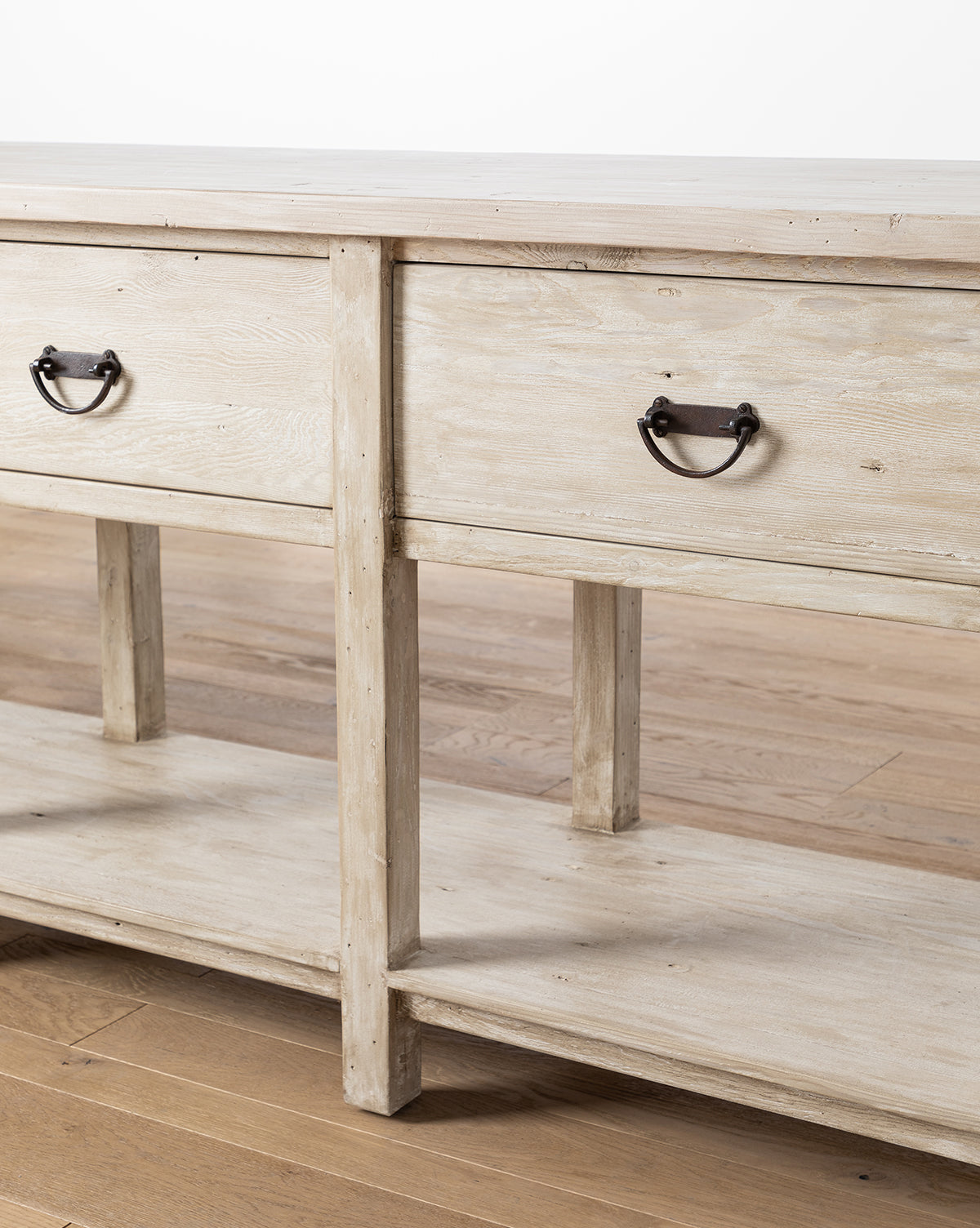 A close-up of the Martha Sideboard, made from reclaimed Douglas Fir, showcases its two metal-handled drawers and open lower shelf on a hardwood floor by McGee & Co.