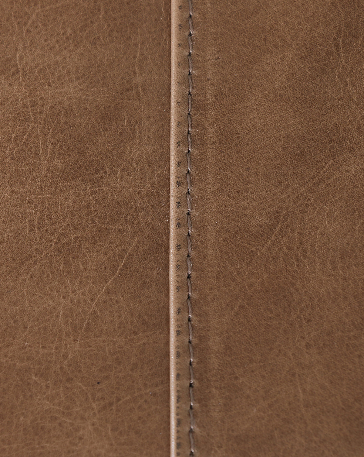 Close-up of taupe leather on the Quincy Bench highlights a visible center seam and detailed stitching, with natural creases and subtle color variations enhancing its texture, by McGee & Co.