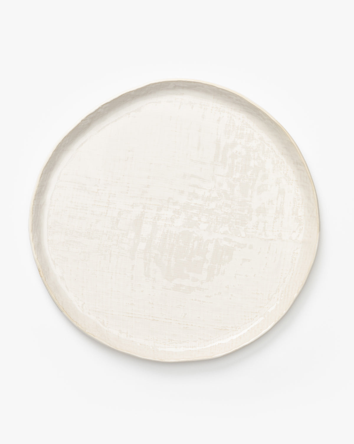 The Radlee Dinner Plate is a round, off-white ceramic plate with a slightly uneven rim and subtle textured surface, highlighting artisan dinnerware craftsmanship, shown on a plain white background by McGee & Co.