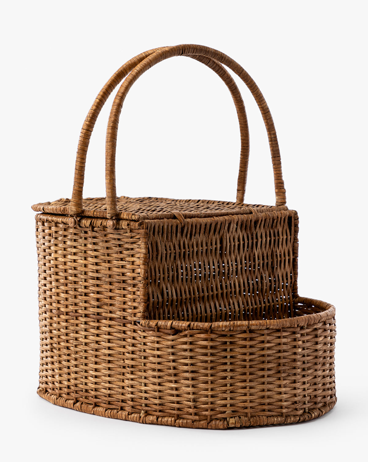 The Rattan Wicker Picnic Basket, featuring two handles, a hinged lid, and a separate lower compartment, provides stylish storage and is shown on a plain white background by McGee & Co.