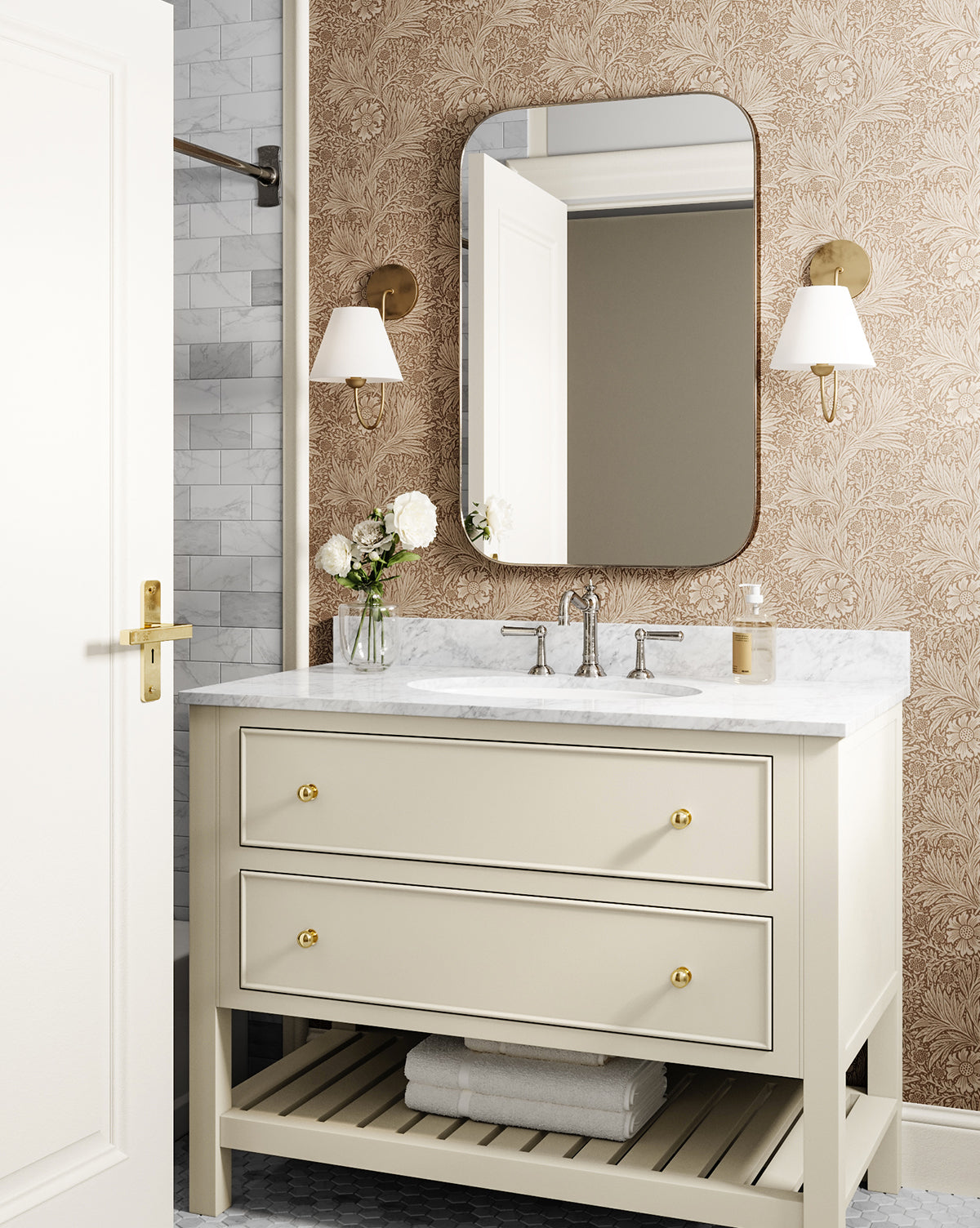 Elegant bathroom with a marble-topped beige vanity, gold hardware, the Jace Inset Rectangle Mirror (shatterproof glass, rounded edges), wall sconces, floral wallpaper, white roses in a vase, and a towel on the lower shelf by McGee & Co.