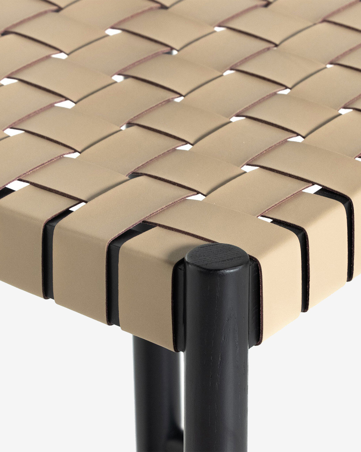 Close-up of the Robson Stool—this kitchen stool showcases a beige woven leather seat and cylindrical black wooden legs, emphasizing the seat’s detailed interlacing pattern, by McGee & Co.