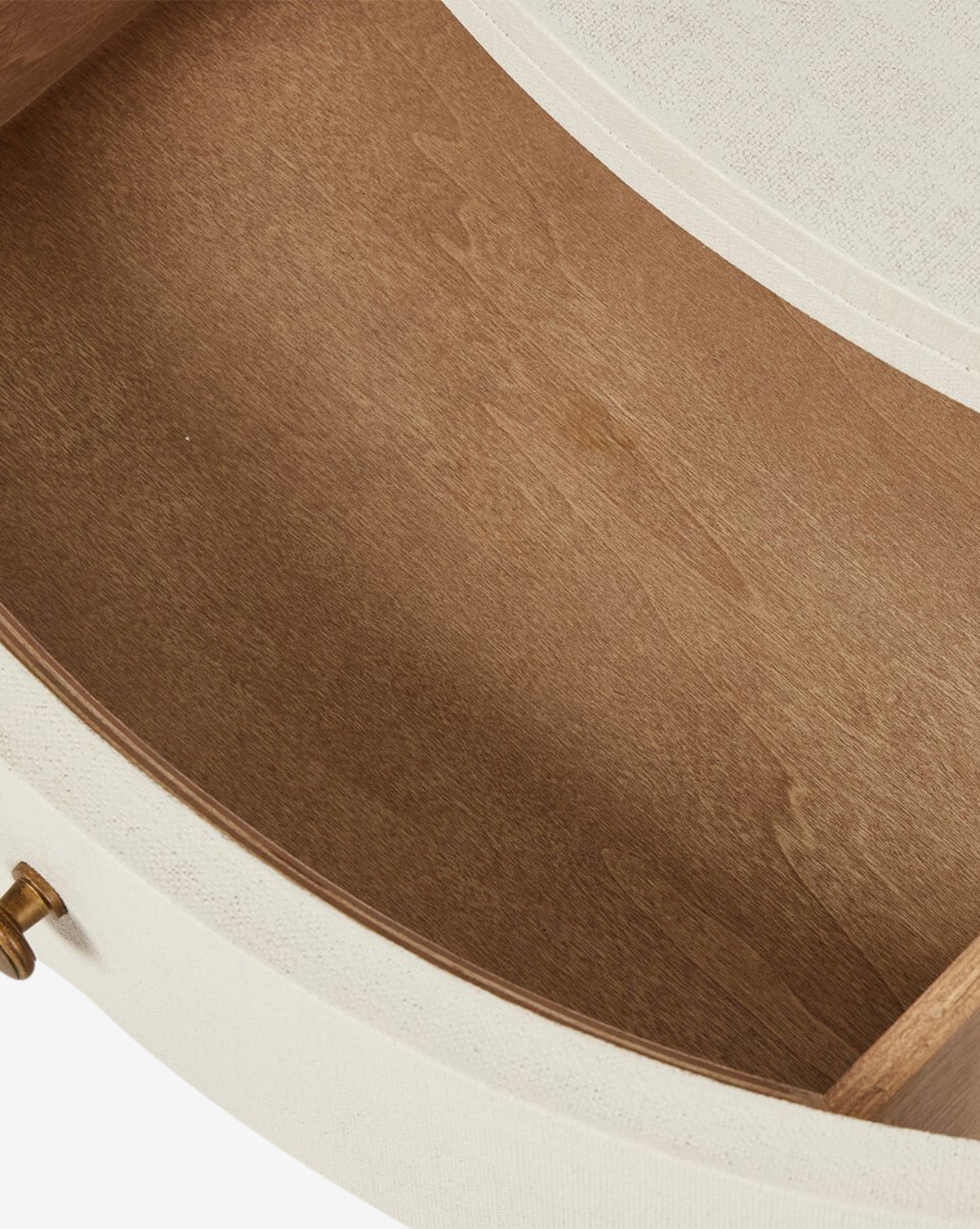 Close-up of the empty, oval-shaped drawer inside the Rosalie Nightstand. It features a light brown wooden interior, a brass handle, and an outer edge upholstered in cream fabric for an elegant bedside storage solution by McGee & Co.