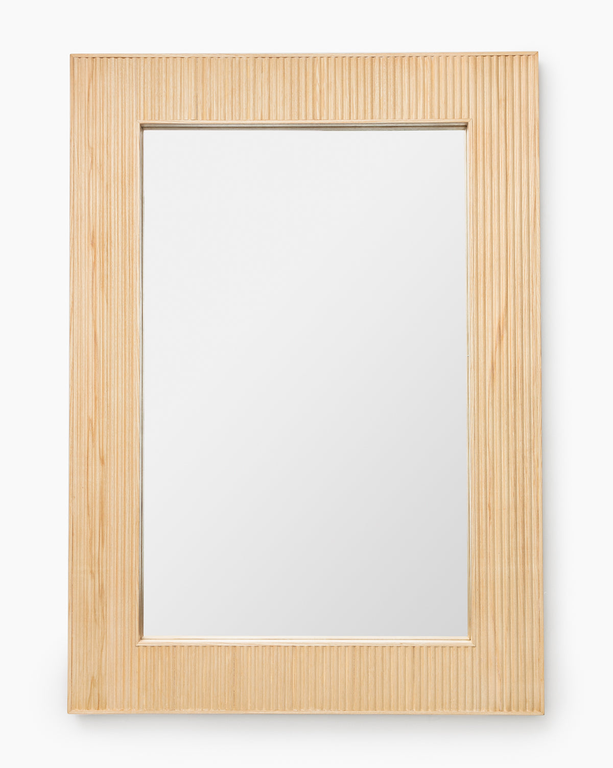 The Rowan Wall Mirror showcases a clear rectangular surface framed by ribbed ash wood with vertical grooves, offering a modern and elegant touch to any room, by McGee & Co.