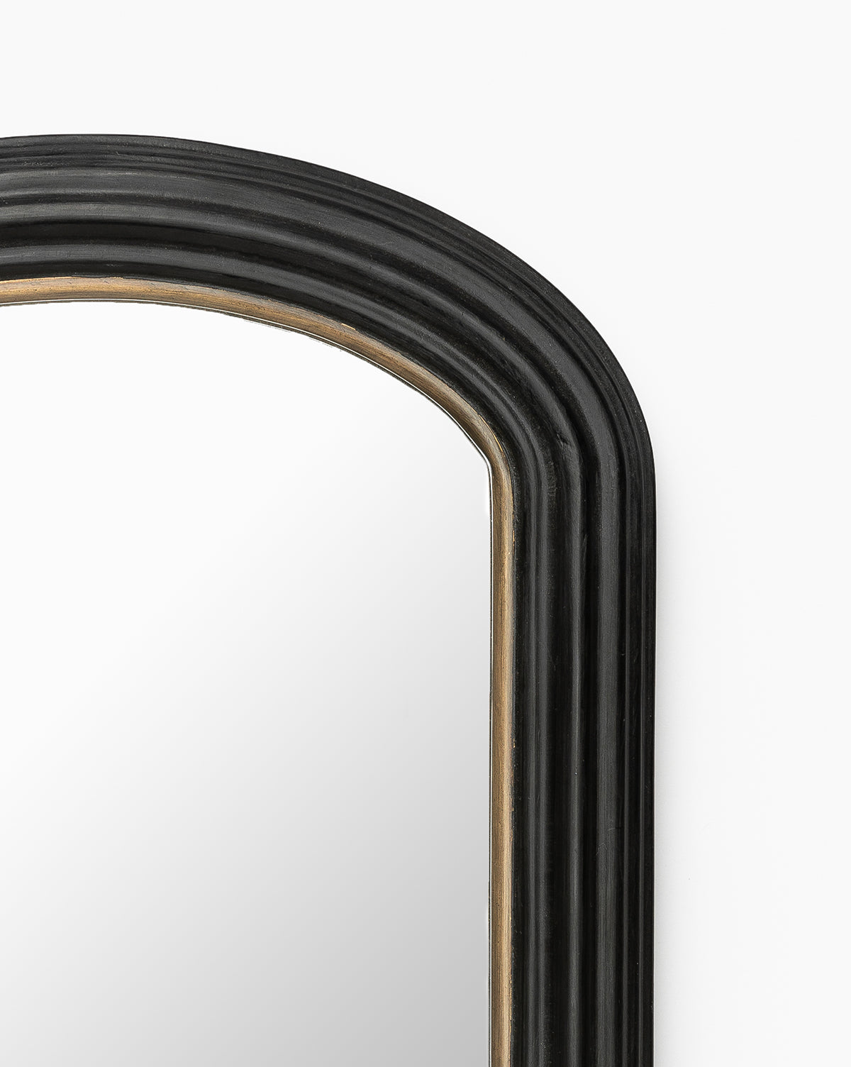 Close-up of the upper right corner of the Samuel Shelf Mirror, featuring a wood frame with a rounded, layered black finish and subtle gold detailing along the inner edge, set against a white background, by McGee & Co.