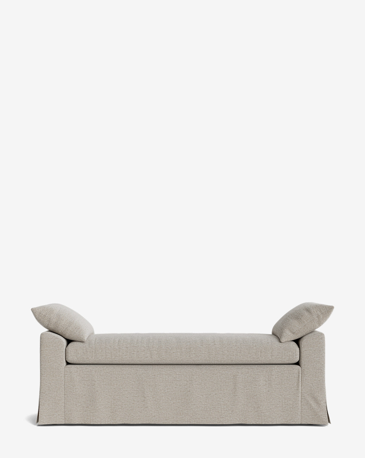 A light gray upholstered sofa with performance fabric, two matching pillows, and a skirted base stands against a plain white background. Its minimalist design pairs perfectly with the Scaletta Bench for a modern look, by McGee & Co.
