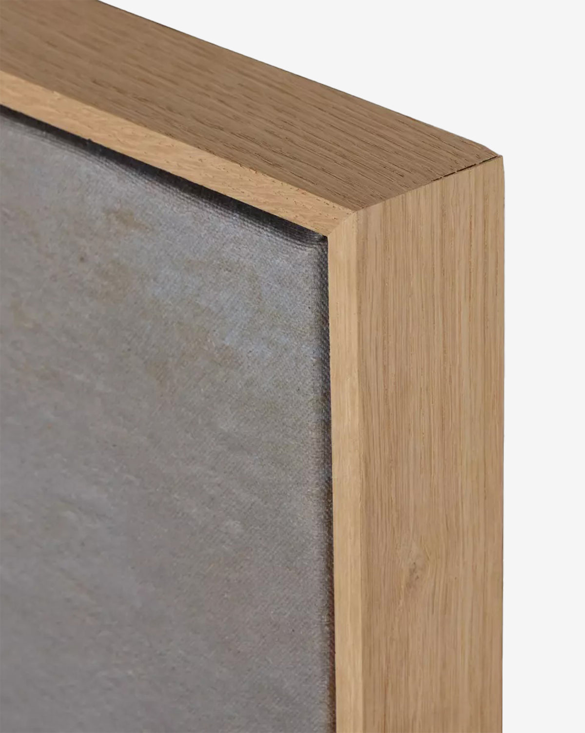 Close-up of the corner of a white oak frame surrounding Seafoam by Aileen Fitzgerald—a stretched canvas with a muted gray surface, ideal for minimalist home decor against a plain white background, by McGee & Co.