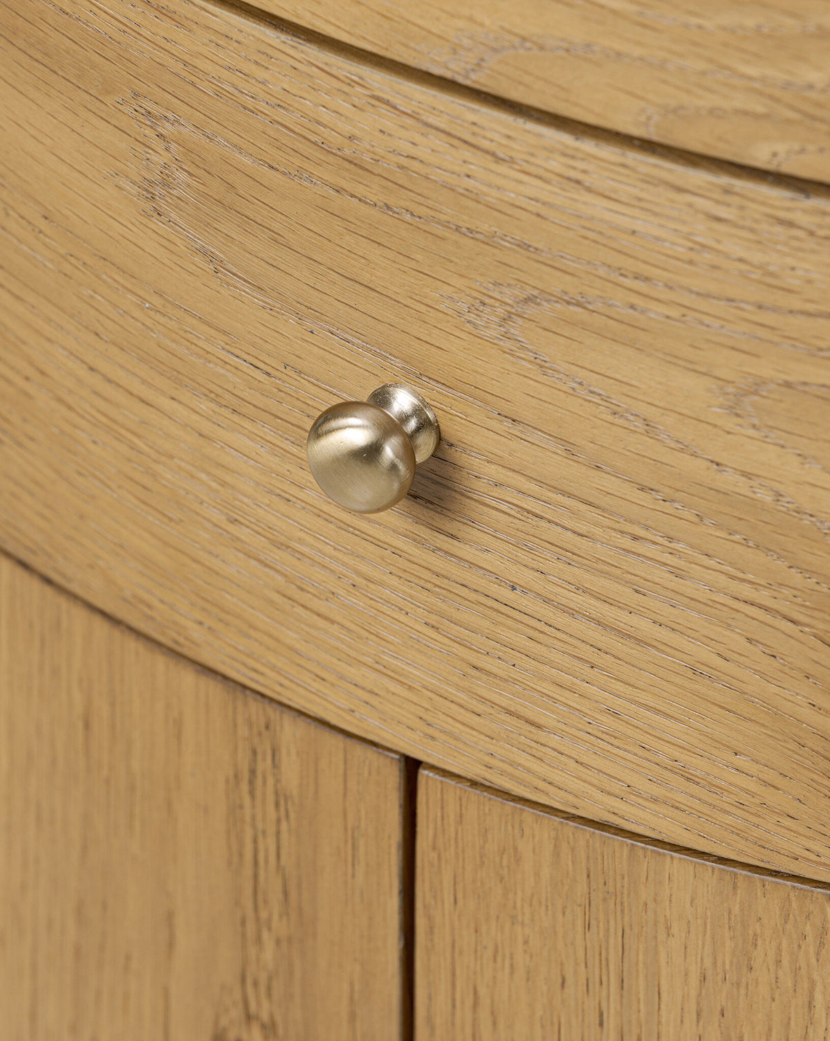 Close-up of the Selma Nightstand’s drawer featuring a curved front, round metallic knob, and visible wood grain—highlighting the modern design of this oak veneer nightstand by McGee & Co.