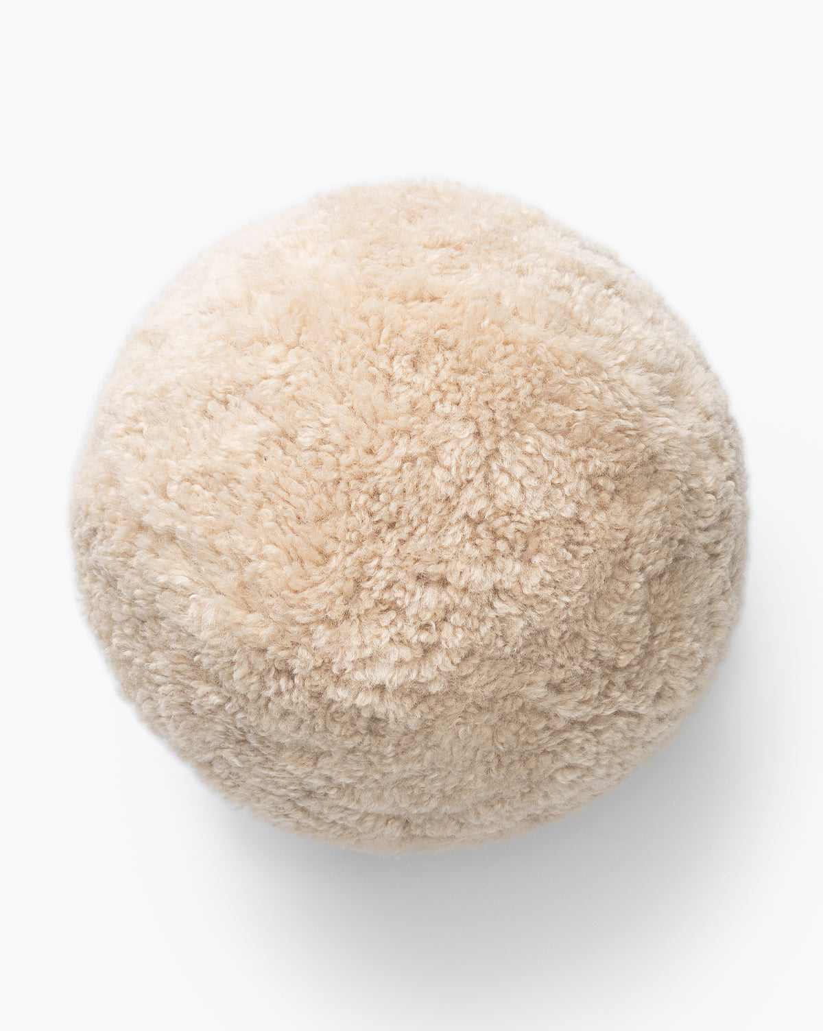 A round, fluffy Sherpa Tan Ball Pillow is photographed against a white background by McGee & Co.