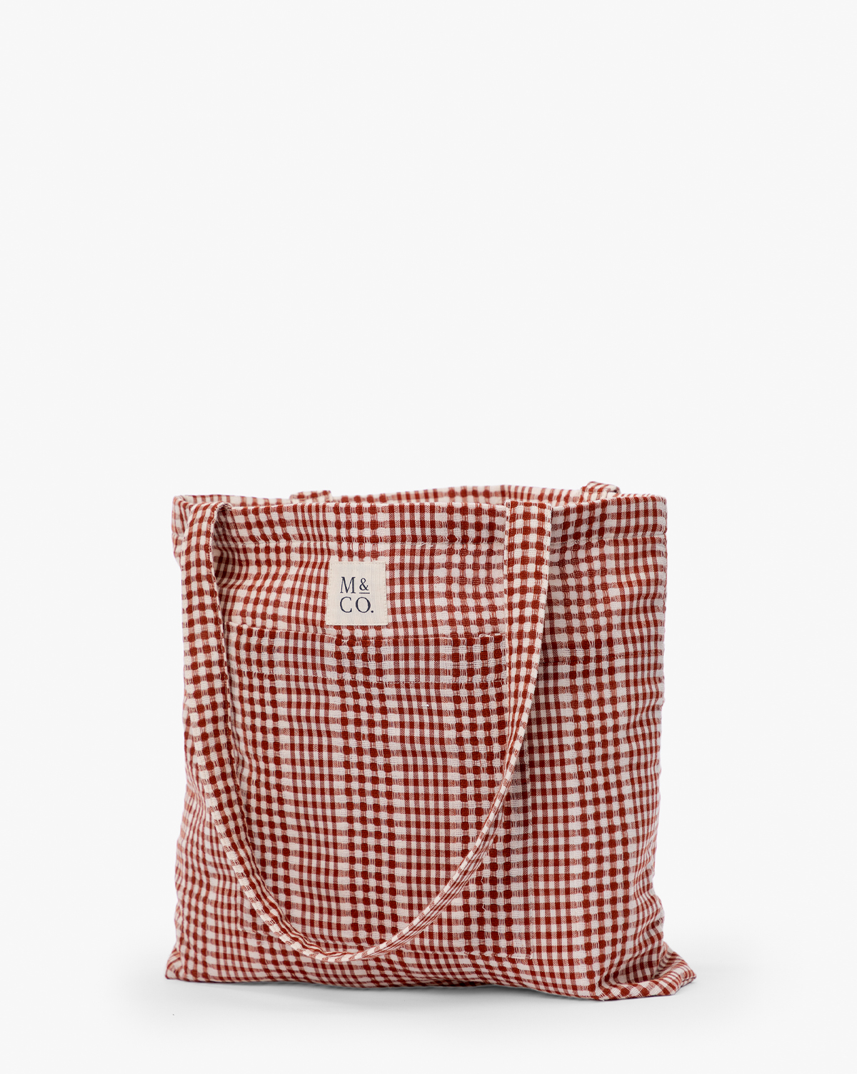 The Spencer Tote Bag is a casual tote with a red and white gingham check pattern, two handles, and a small square label reading "M & CO." at the top center, by McGee & Co.