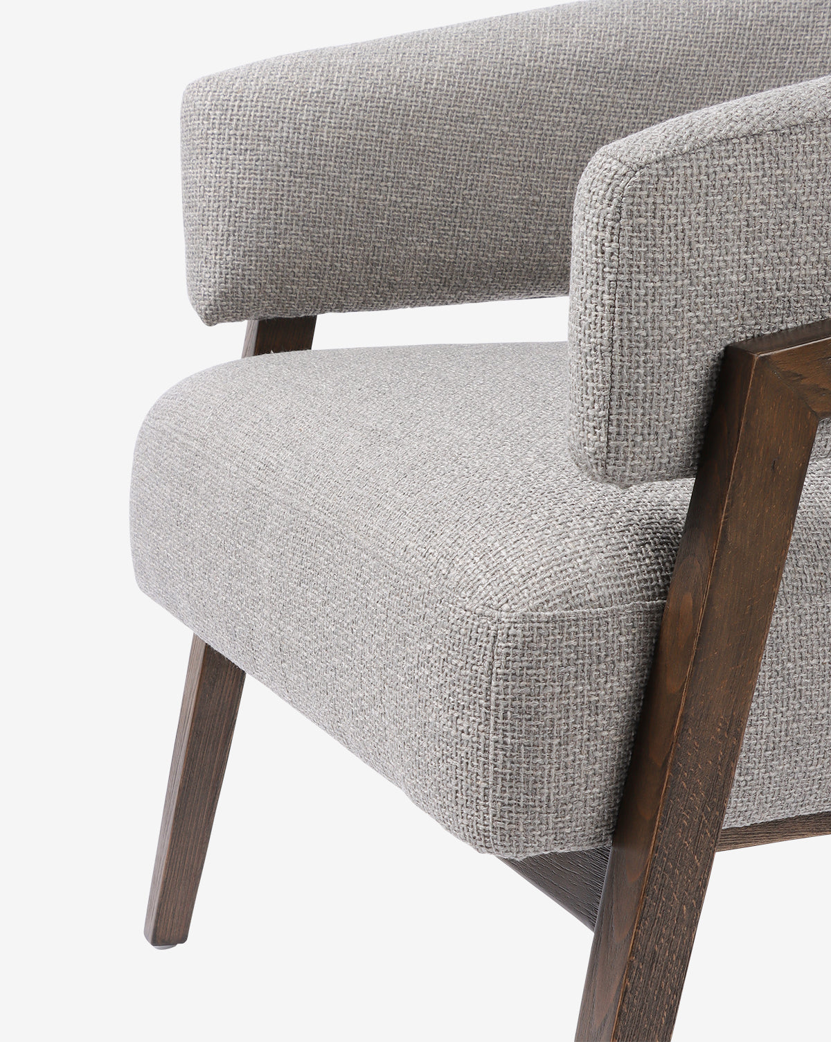 Close-up of the Stanley Lounge Chair, featuring light gray textured upholstery and angled wooden legs and armrests, highlighting its contemporary design against a white background, by McGee & Co.