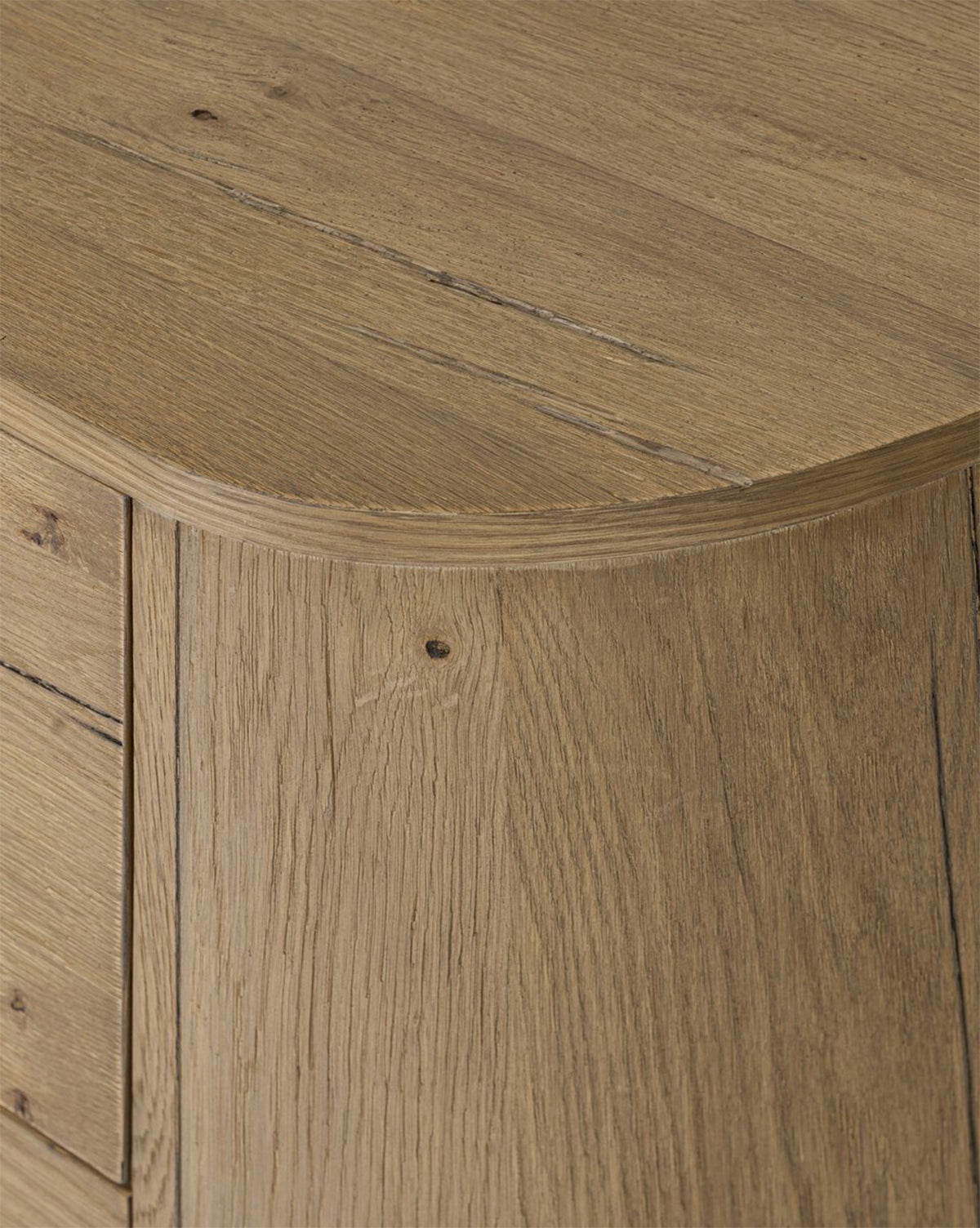 Close-up of the Steffon Nightstand’s corner, showcasing acacia wood with natural grain, light brown color, and visible knots. Its smooth rounded edge and fitted panels add refined style to any bedroom by McGee & Co.