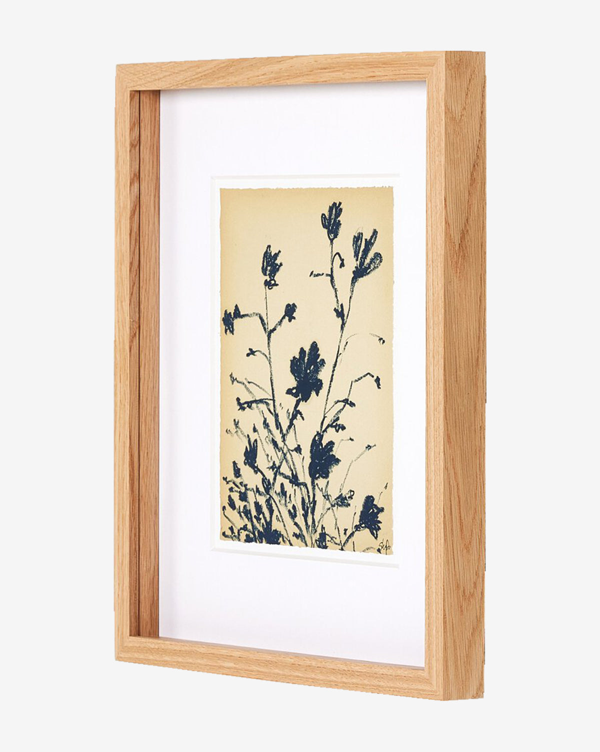 A side view of the gallery-quality artwork Summer Weed by Shaina Page, a wooden-framed botanical print with dark blue flowers and stems on a light beige background, displayed against a plain white surface, by McGee & Co.