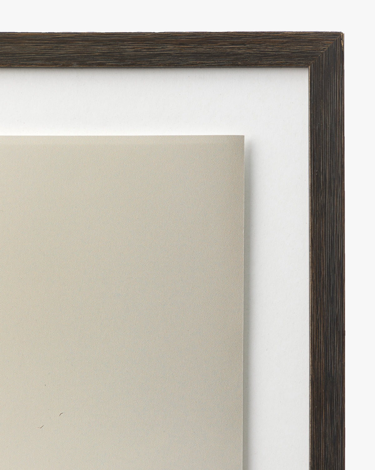 Close-up of the walnut wood frame corner with dark grain finish and white matting, partially framing the Sunday Fog beige giclee print against a white background.