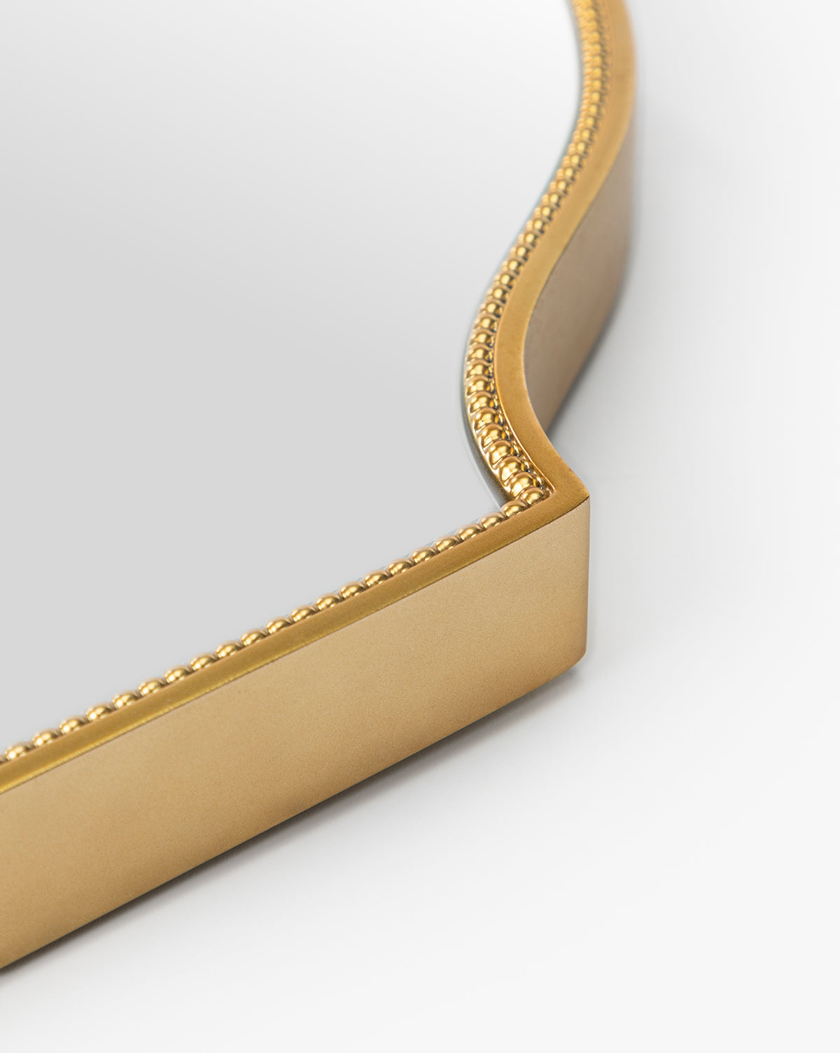 Close-up of the Sussex Wall Mirror showcasing its gold beaded frame with curved corner detail, set against a plain white background, by McGee & Co.