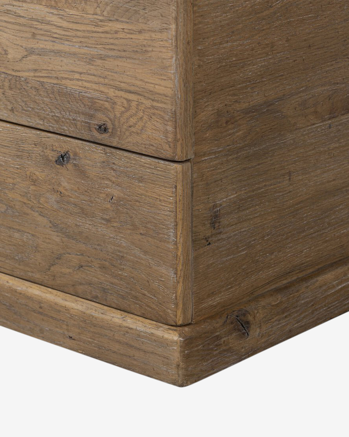 Close-up of a Sutton Trunk wooden drawer corner, highlighting natural wood grain, knots, and weathered oak texture—ideal for storage—set against a white background, by McGee & Co.