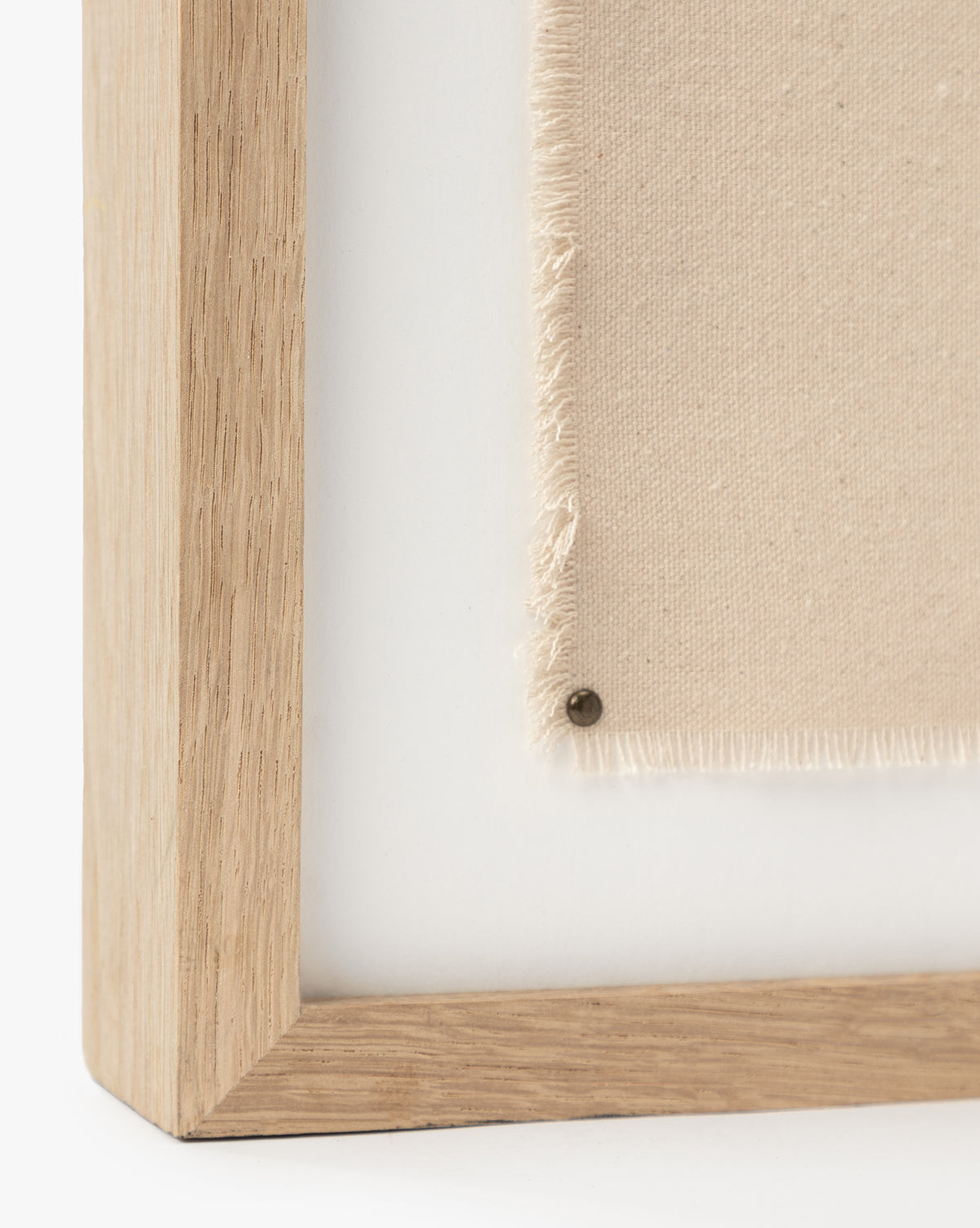 Close-up of a white oak frame corner holding cream-colored, slightly frayed fabric, secured by a small metal pin on a white background. Ideal for displaying Swath 2 Sepia as abstract art or a giclee print.